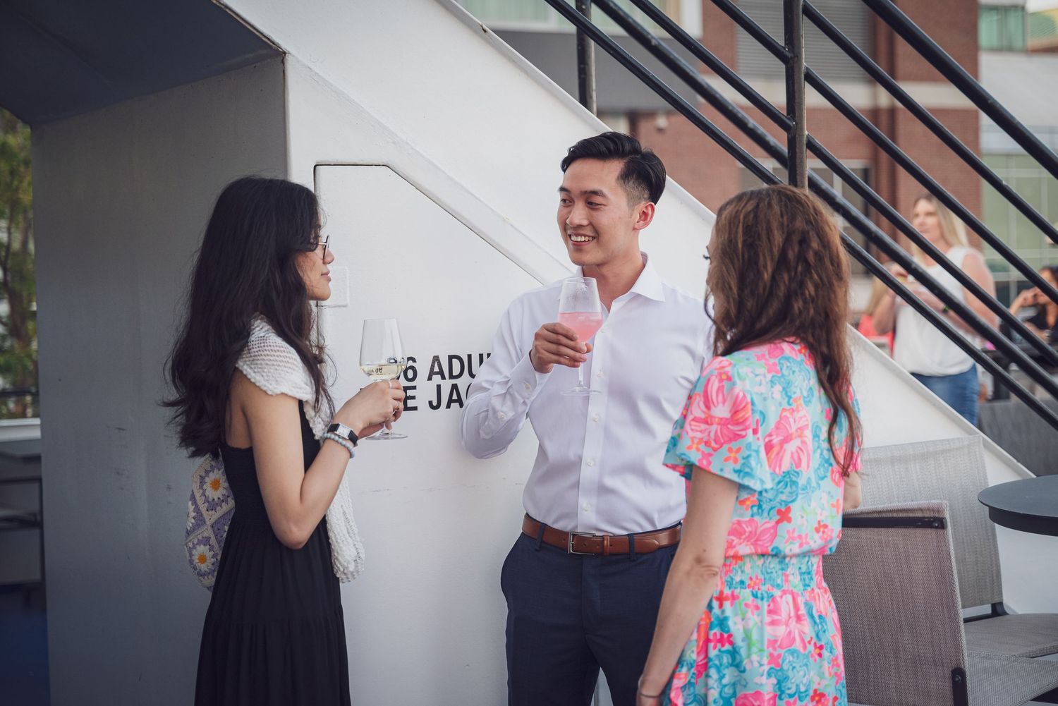 A group of people interacting and smiling during a casual gathering in a bright indoor space.
