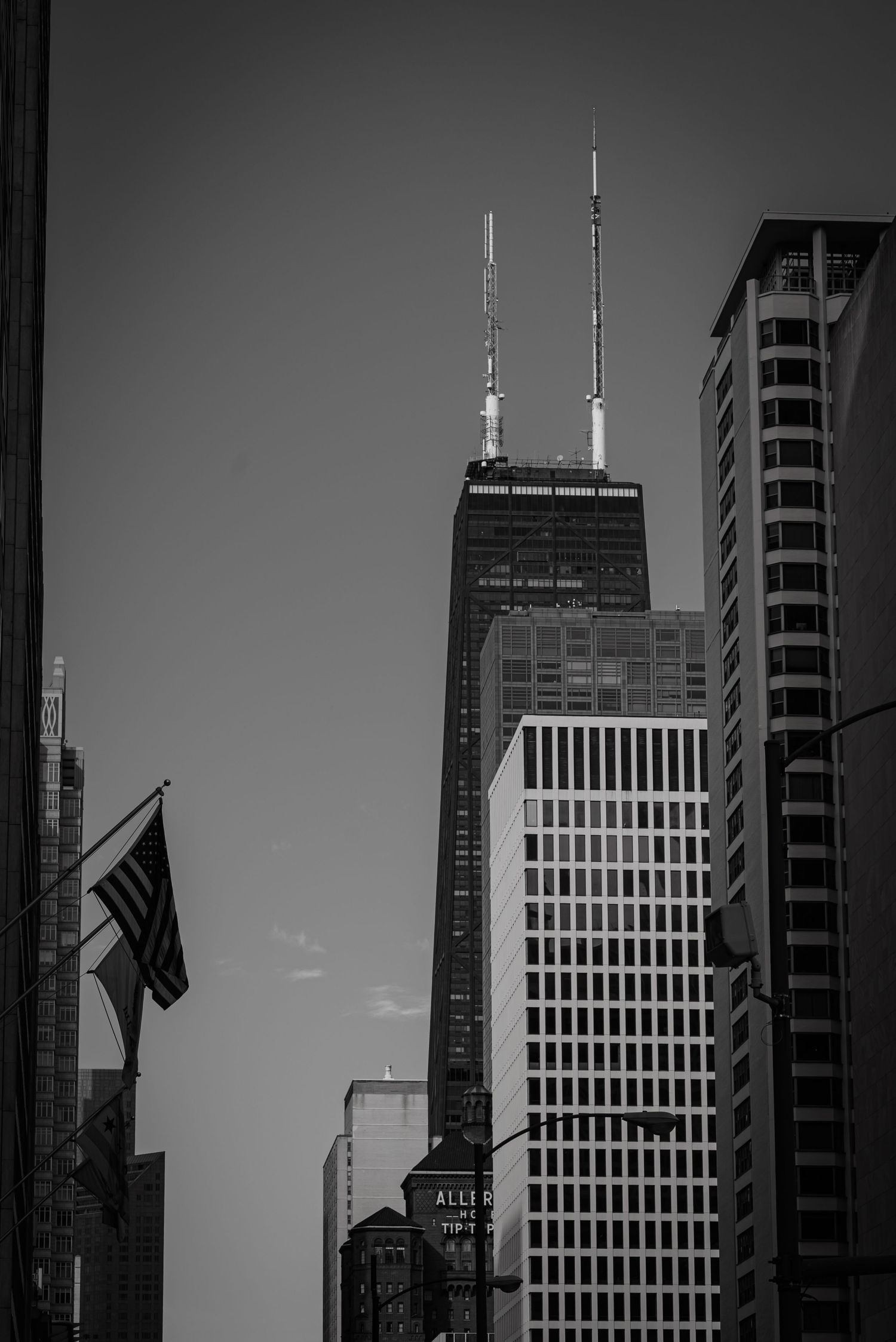 Black and white view of John Hancock Center skyscraper with American flag in Chicago. goose.img photography LLC - Chicago Photographer