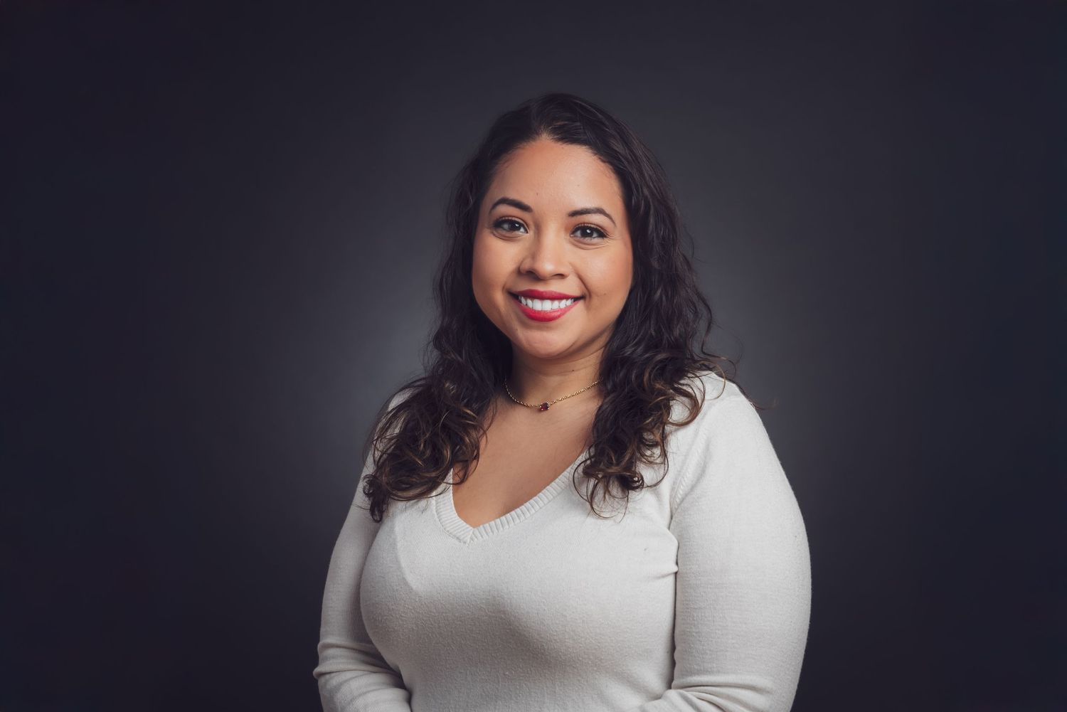 A professional studio portrait against a dark background showcasing warmth and confidence. goose.img photography LLC - Chicago Photographer