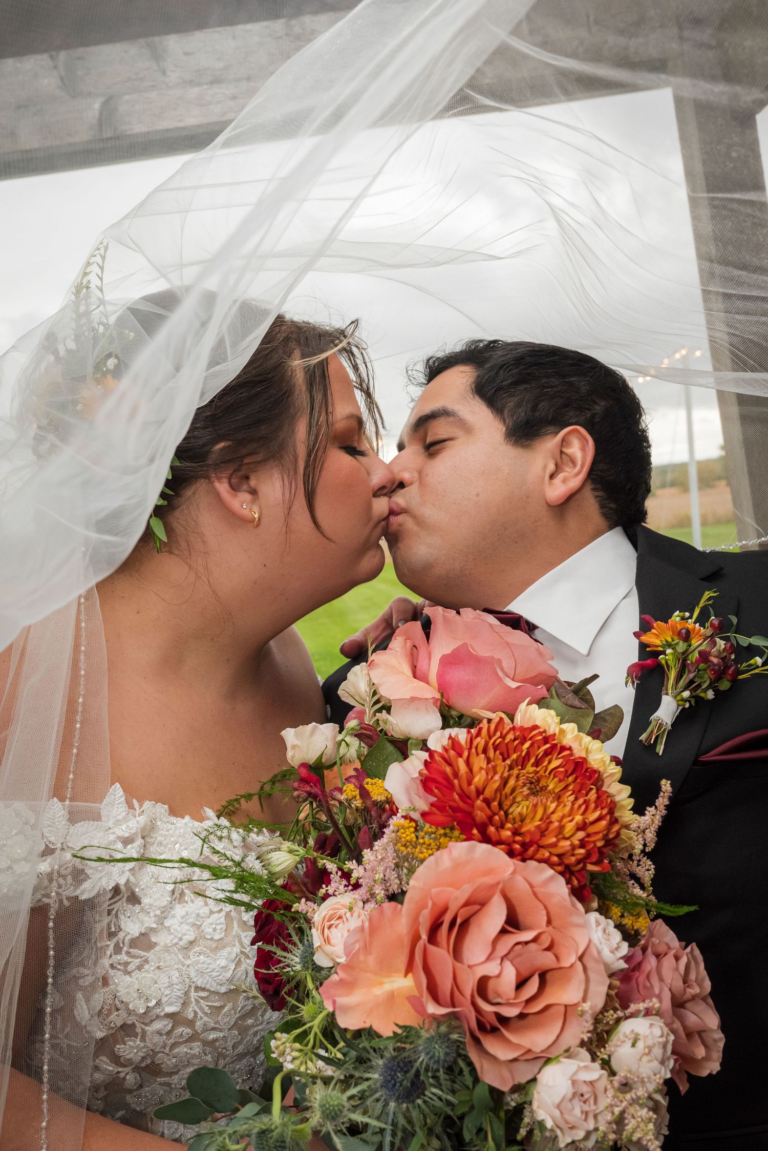 A romantic wedding kiss sequence with a colorful autumn bouquet of roses and chrysanthemums in the foreground.