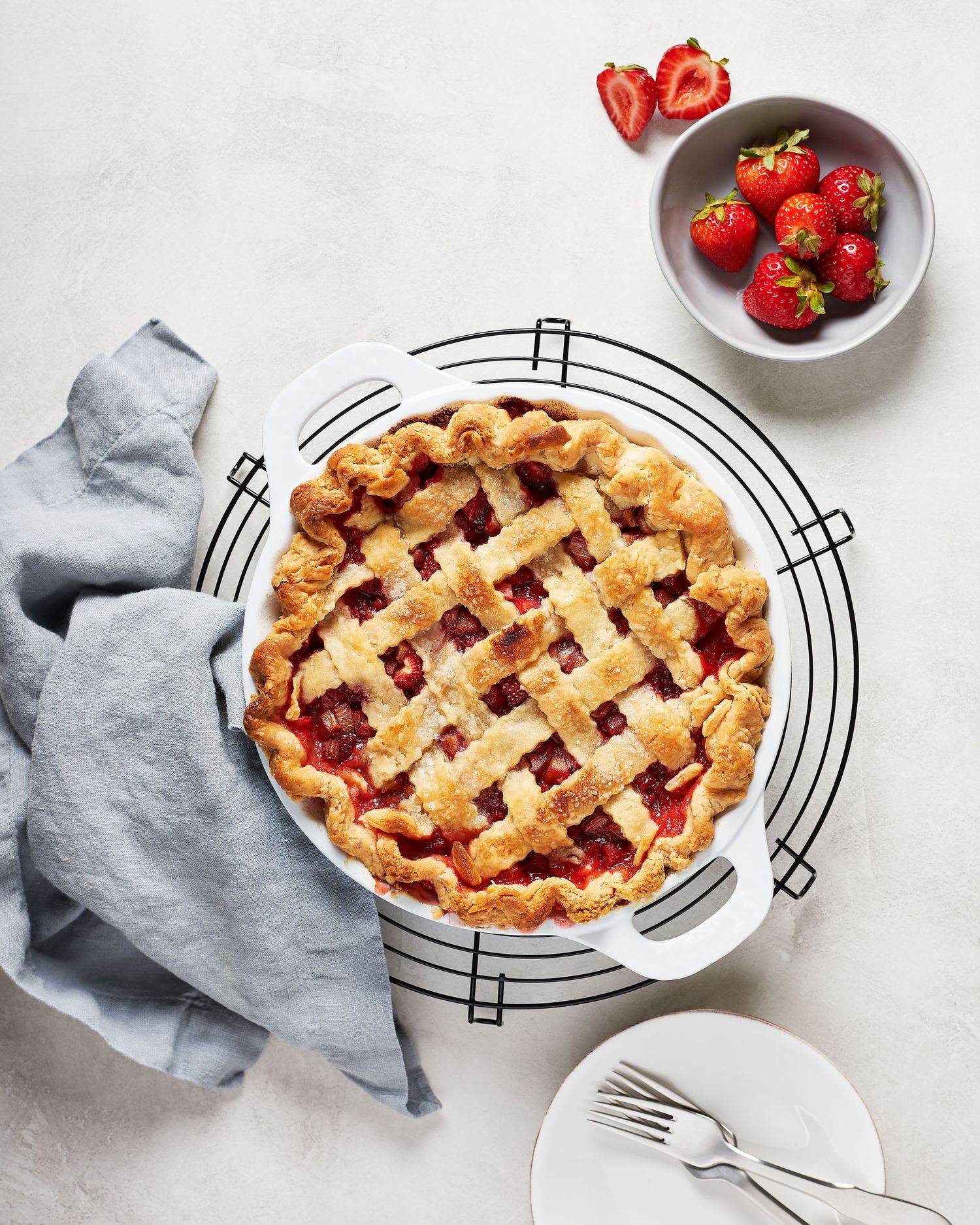 Homemade lattice-topped strawberry pie with fresh berries in a decorative pie dish.
