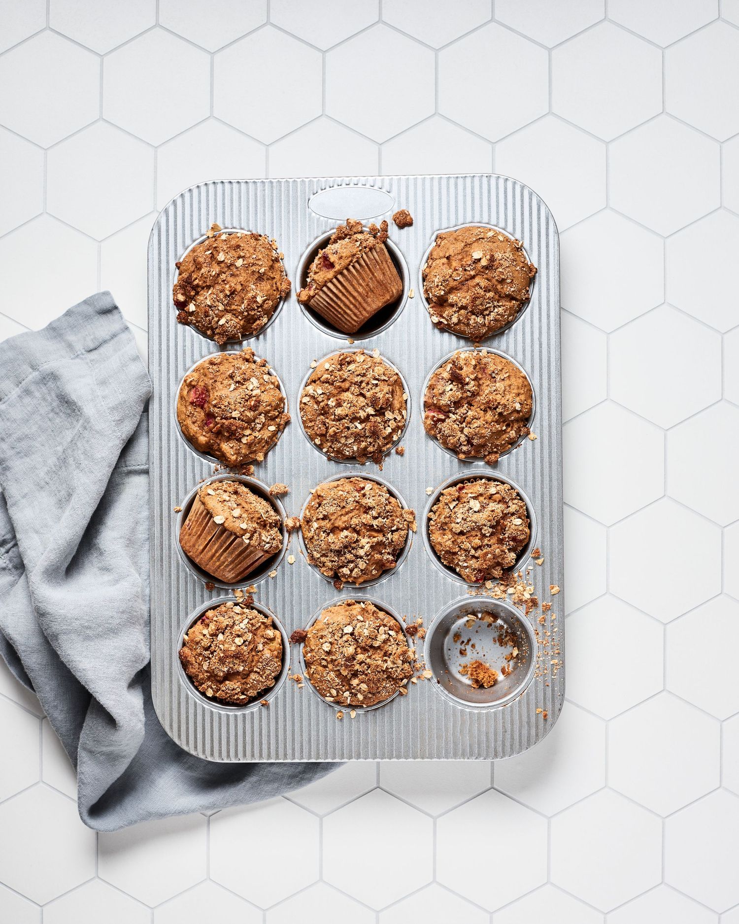 Fresh baked rhubarb muffins in a metal tin with hexagonal tile background.