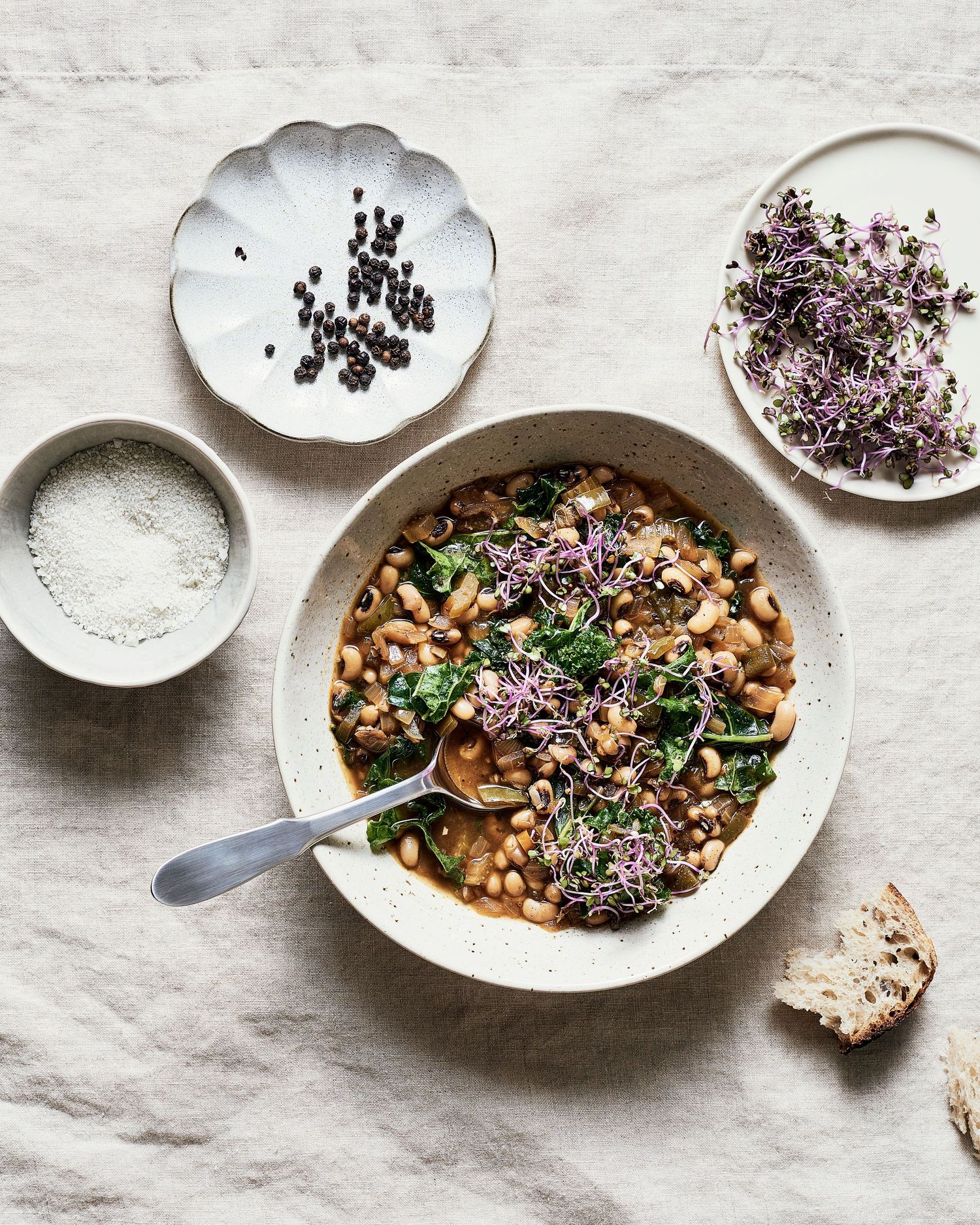 Rustic bowl of black-eyed pea stew topped with microgreens and garnishes.