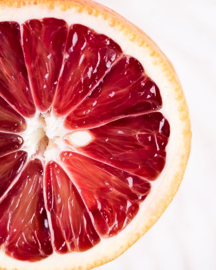 Close-up macro shot of halved blood orange showing vibrant red segments.