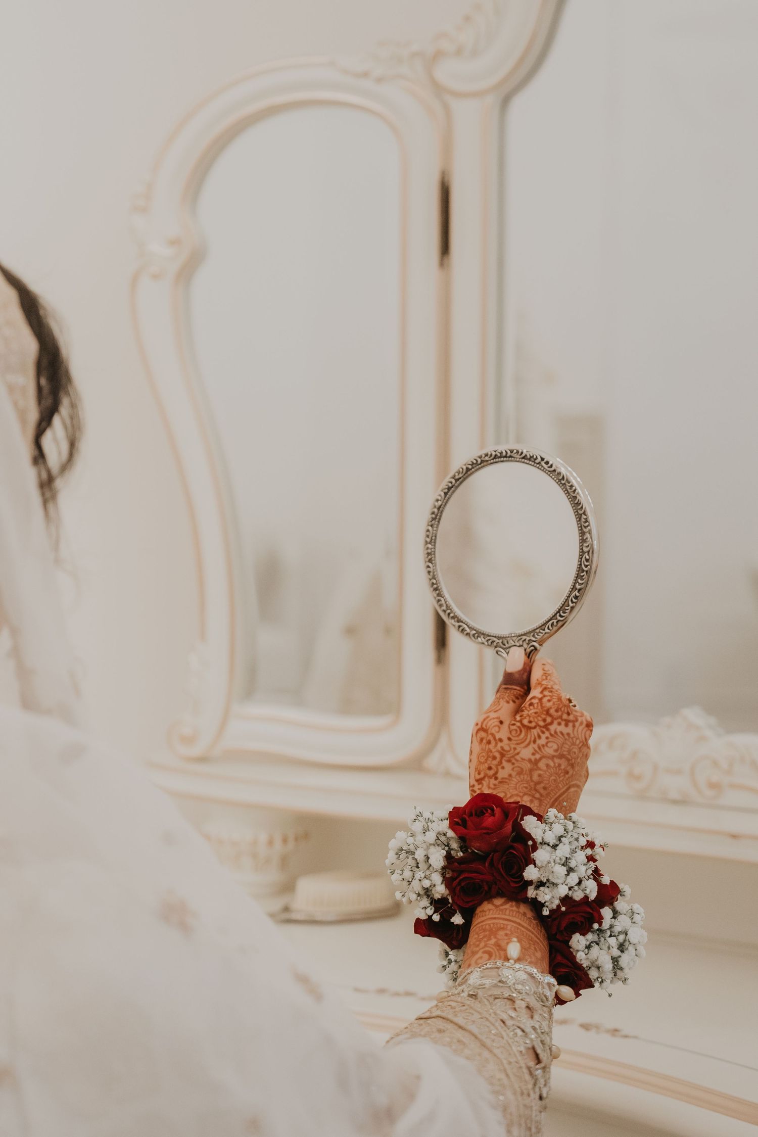 Toronto Pakistani Muslim wedding photographer captures a mehndi bride in a red lehenga & groom in black sherwani beneath an elegant white fl
