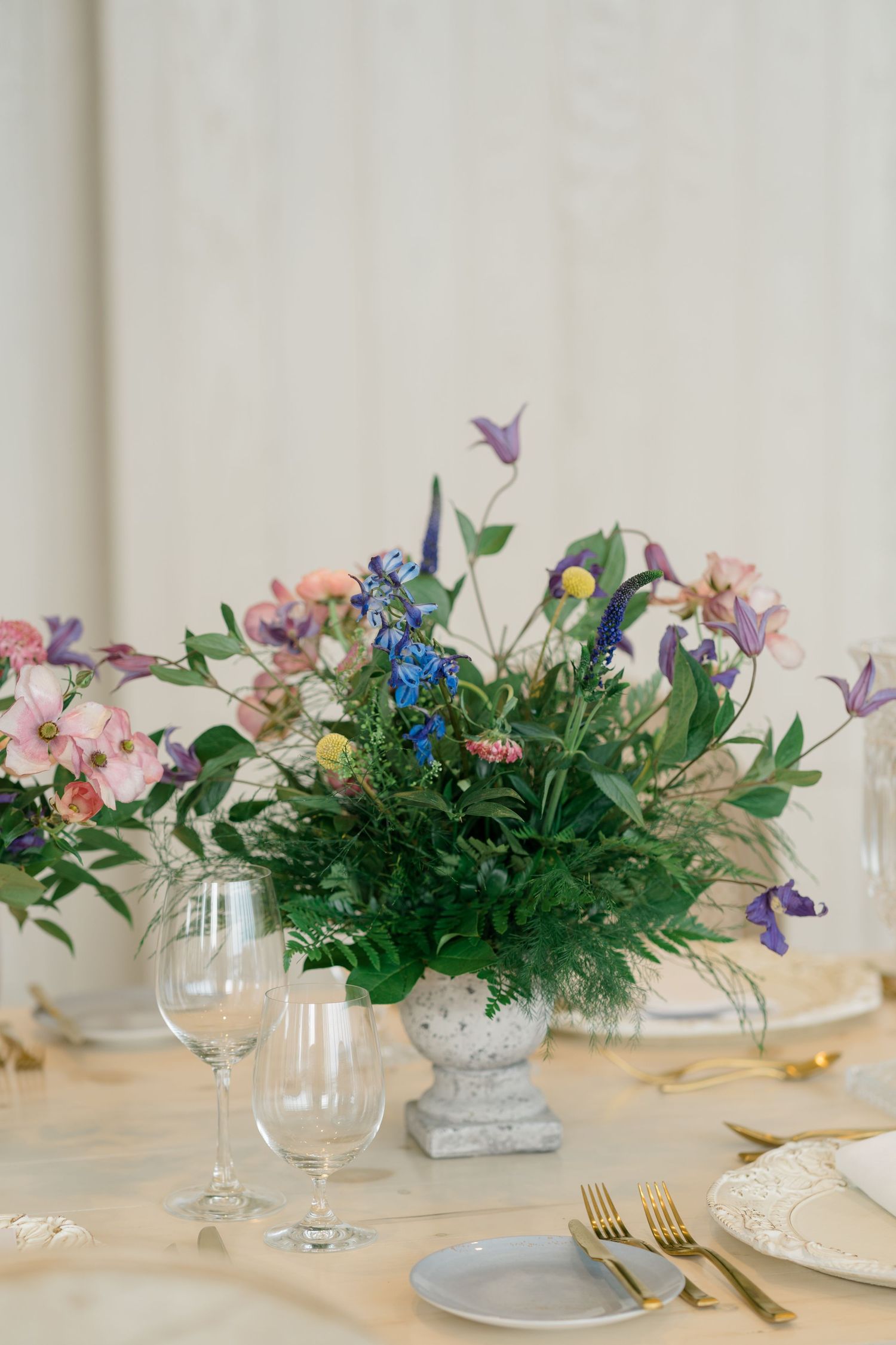 Toronto Muslim wedding photographer captures  luxury tablescape with a wildflower centerpiece in a stone urn, pastel blooms, and gold accent