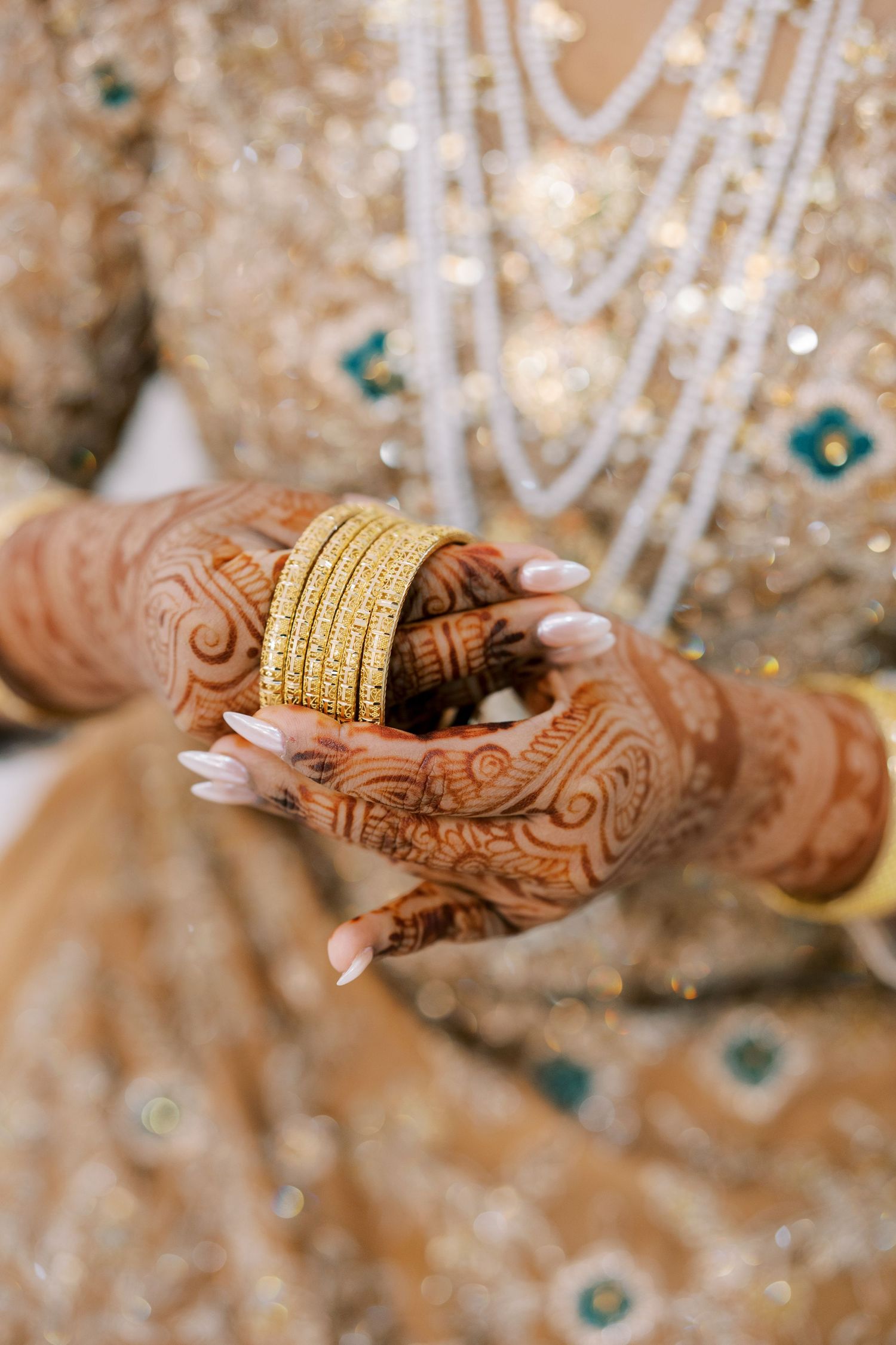 ChatGPT said:
Toronto Muslim wedding photographer captures a mehndi bride holding gold bangles, showcasing intricate henna designs