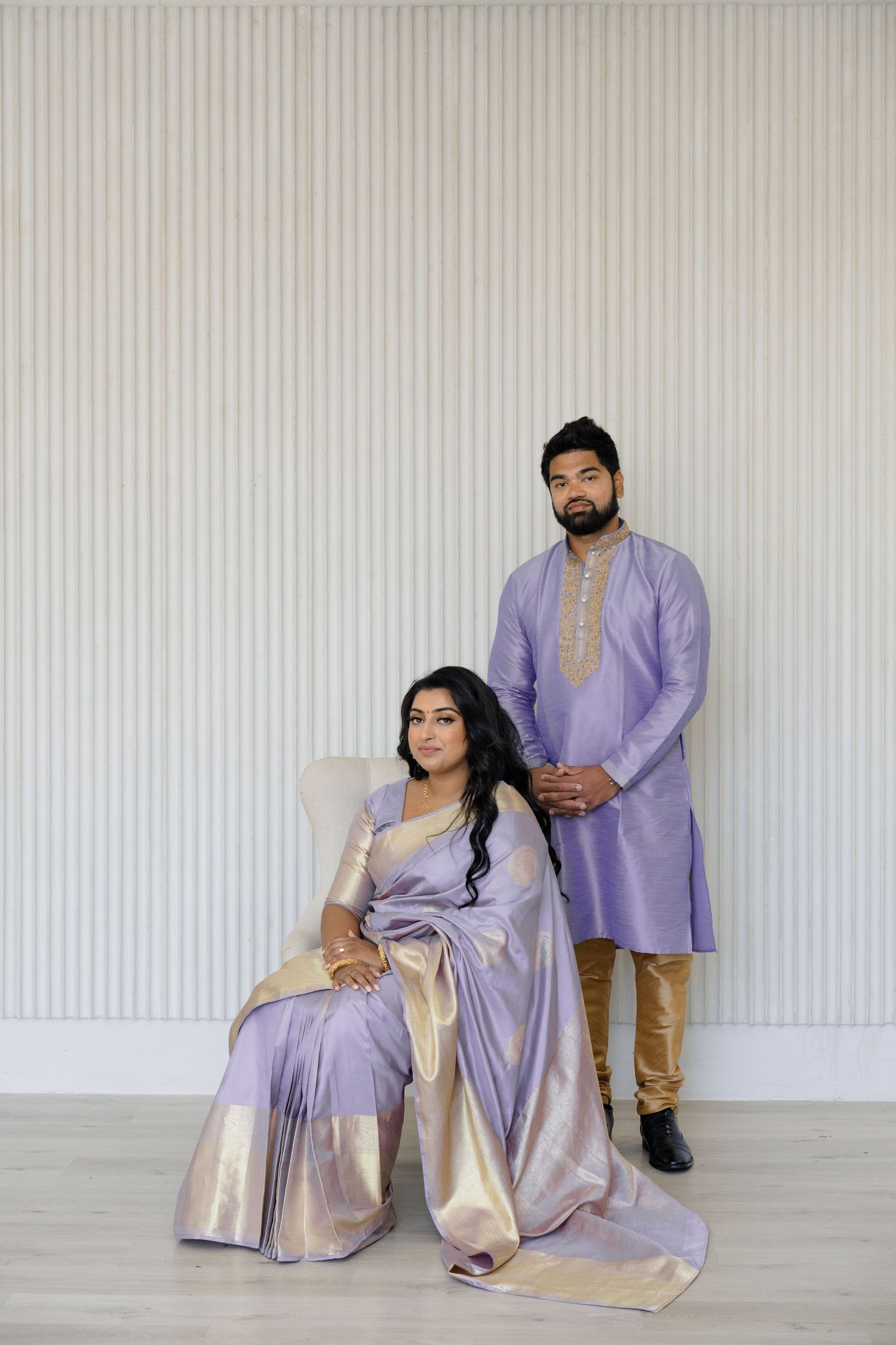 Toronto Pakistani Muslim wedding photographer captures a mehndi bride in a red lehenga & groom in black sherwani beneath an elegant white fl