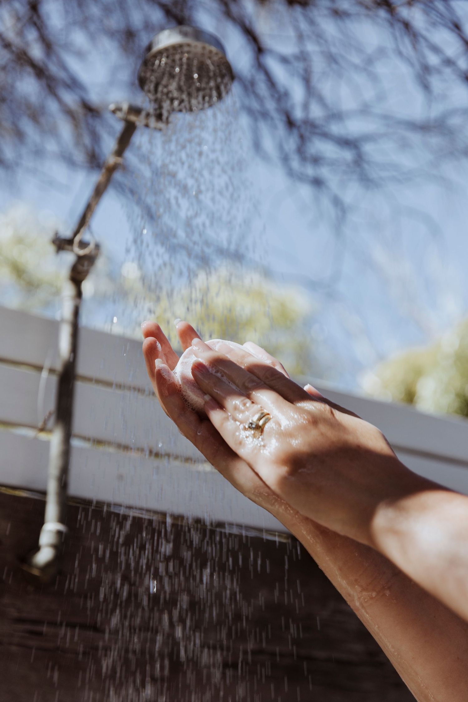 Hands rubbing Seed and Sprout shampoo bar under outdoor shower at My Sister And The Sea Airbnb