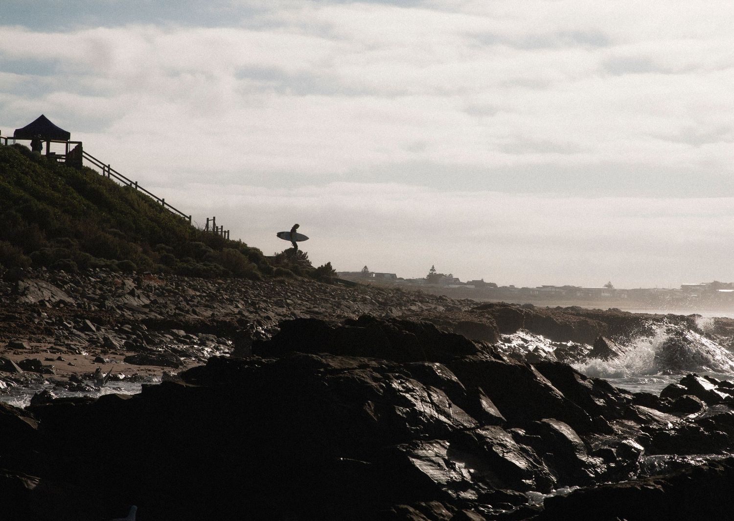 Silhouette of surfer walking from competition tent to the surf at sunrise, Middleton, Fleurieu Peninsula, South Australia