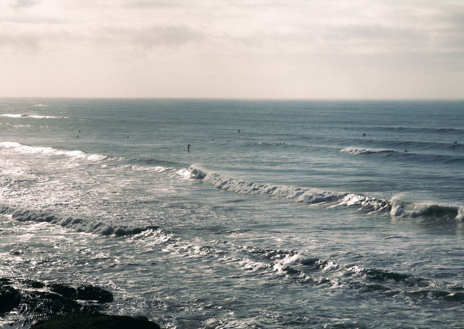 A scene of surfers in the waves at sunrise at Middleton Point, South Australia