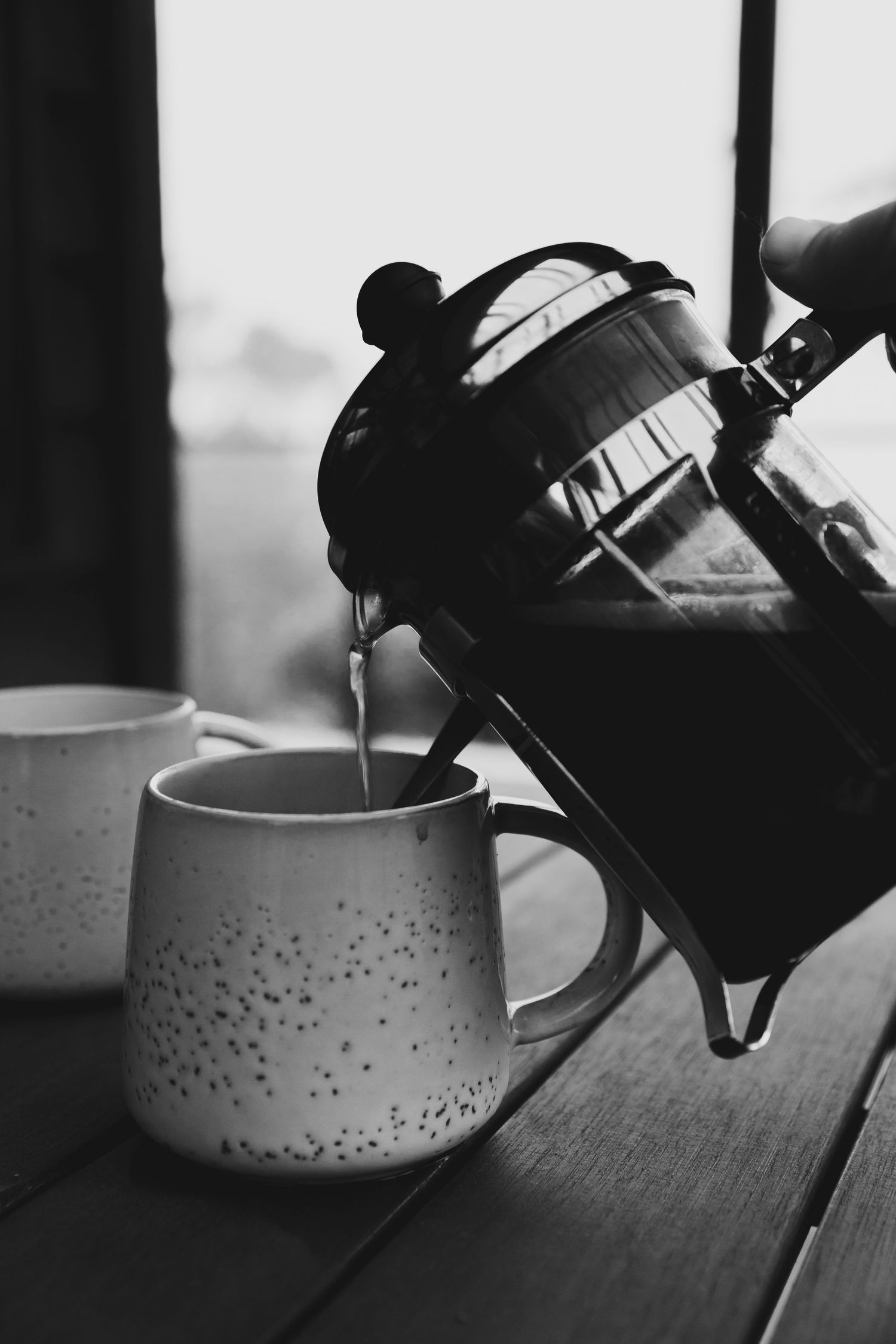 Black and white image of coffee being poured into cup