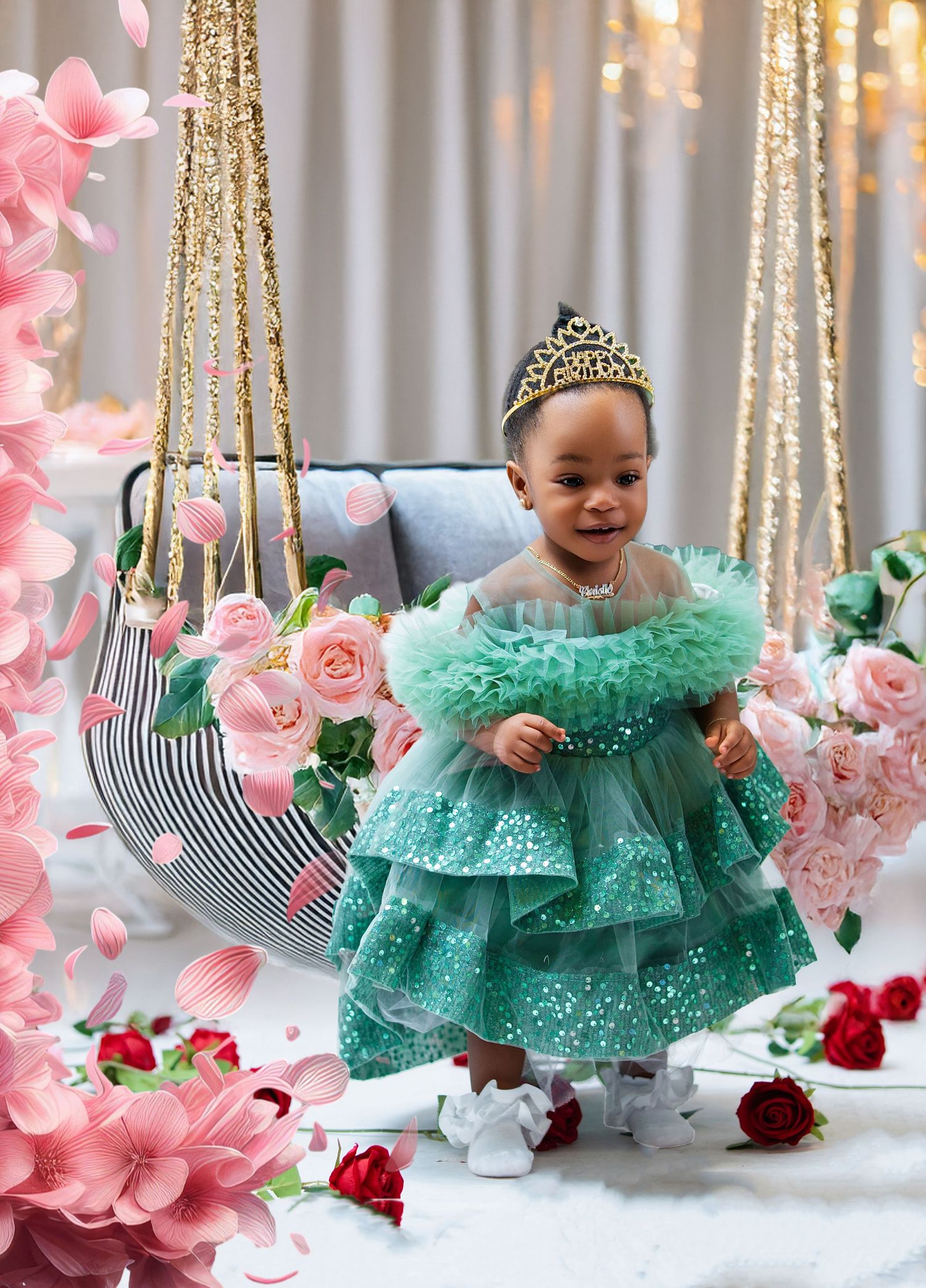 Toddler girl in green sequin tulle dress with tiara poses by floral swing for birthday photo.