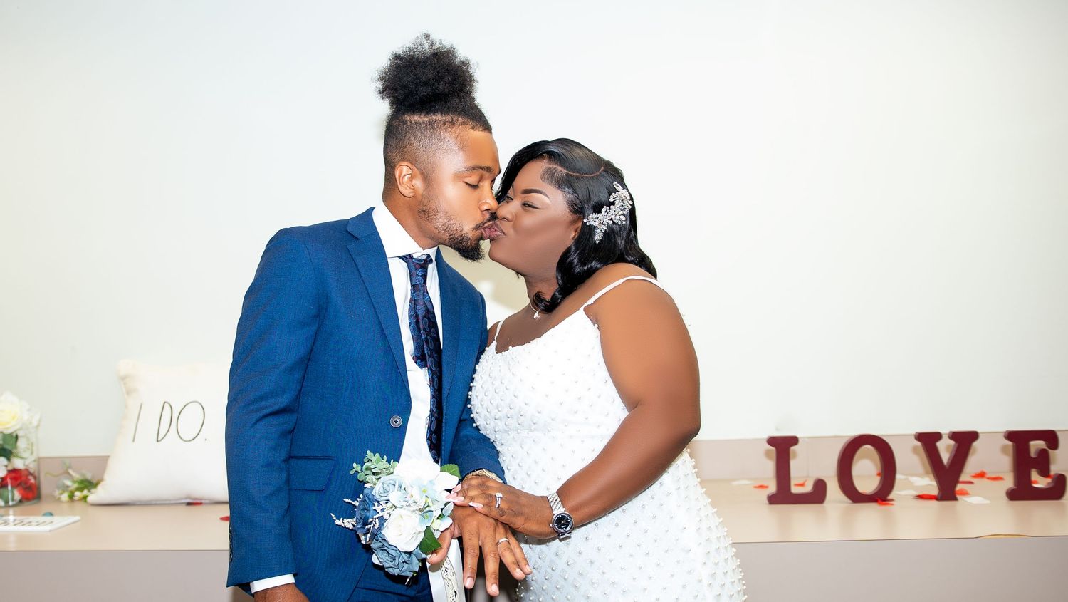 Newlyweds share loving moments in front of a LOVE sign at their wedding celebration.