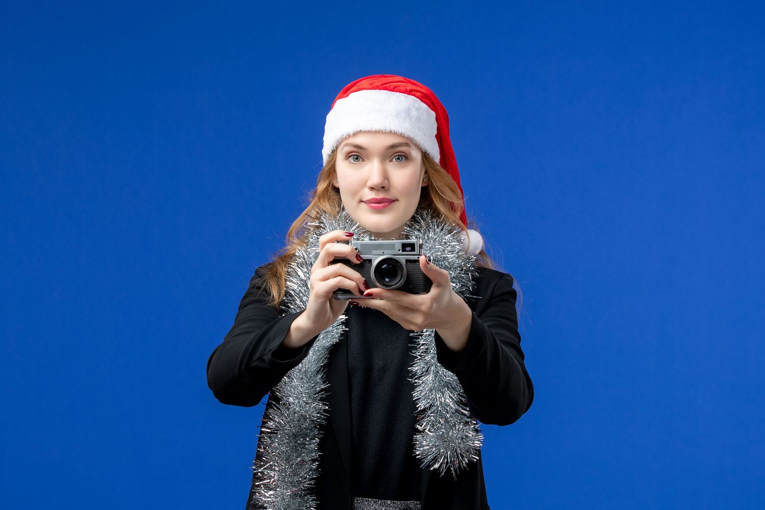 Winter portrait series against blue background wearing Santa hat.