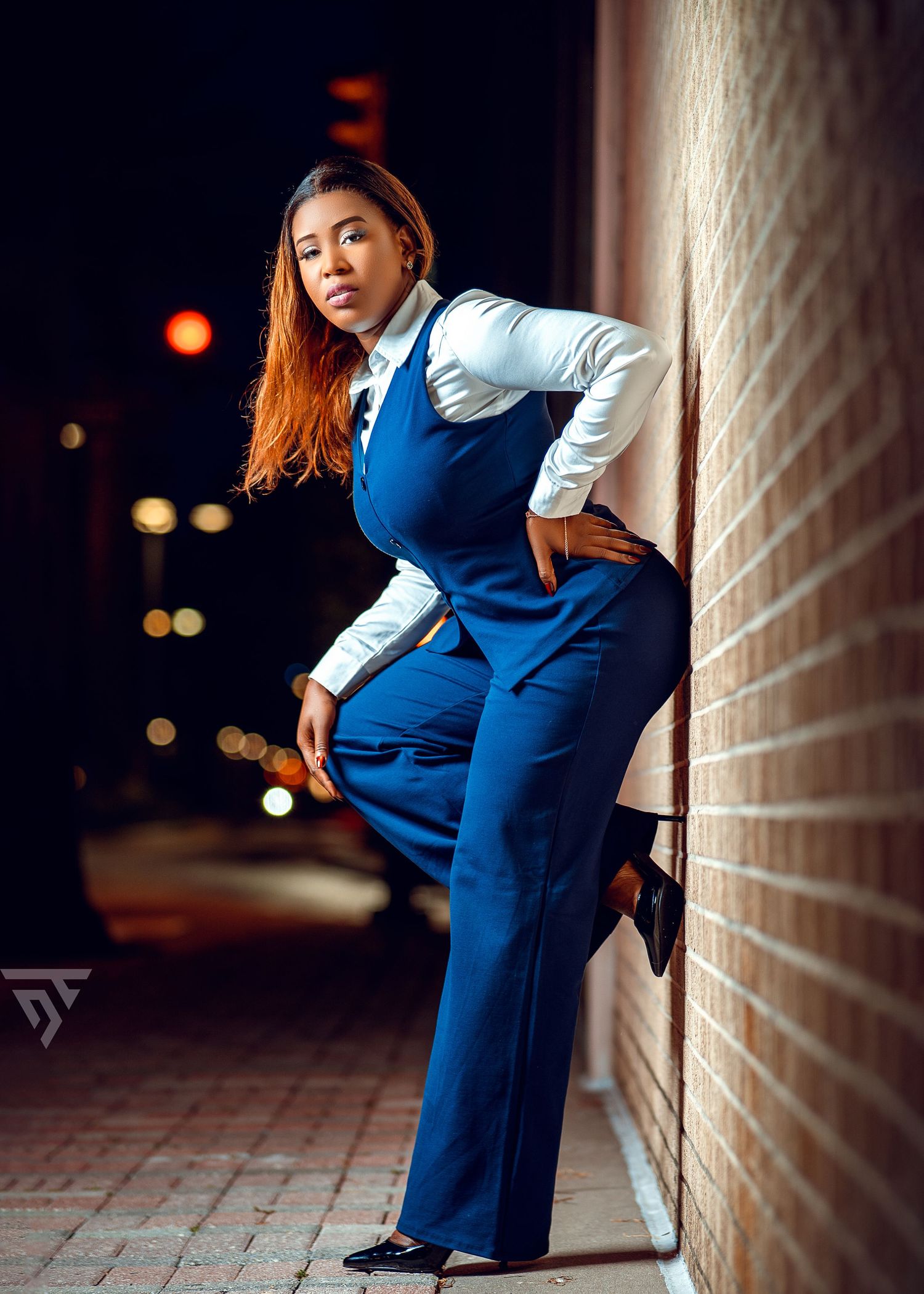 Professional business look with blue vest and white shirt against brick wall.