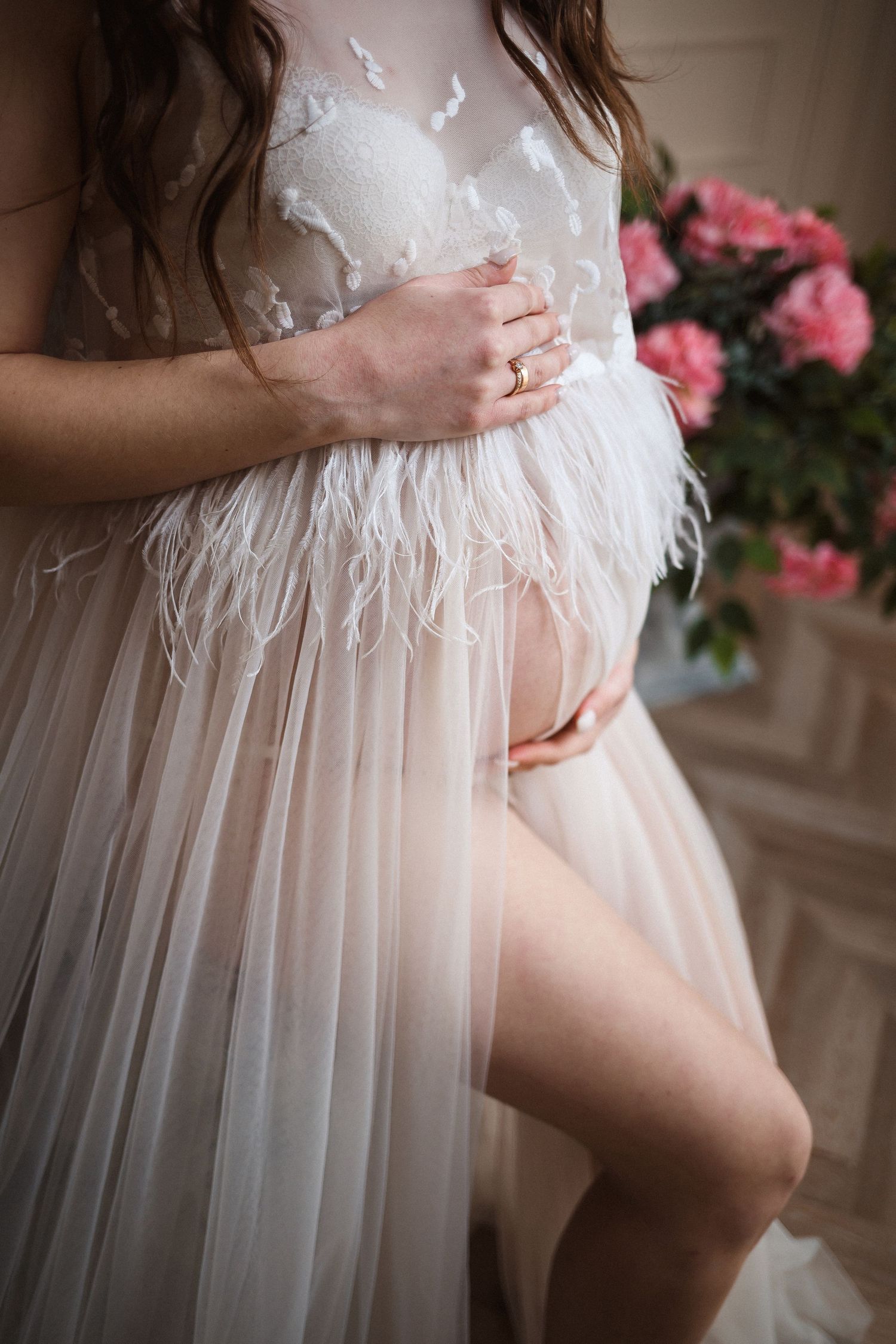 Close-up details of delicate white tulle maternity dress with pink flowers.