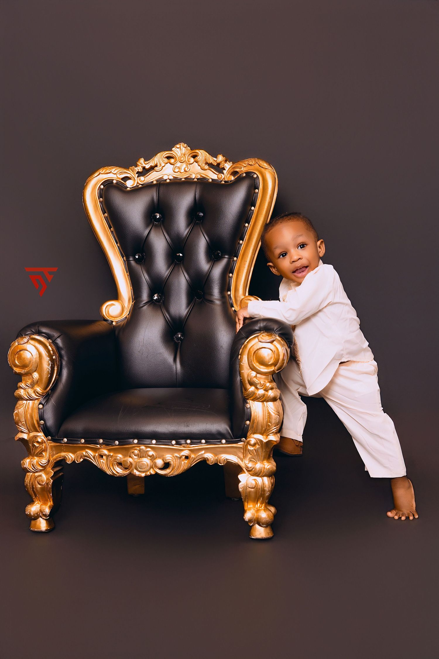Baby playing around ornate black and gold baroque style couch.