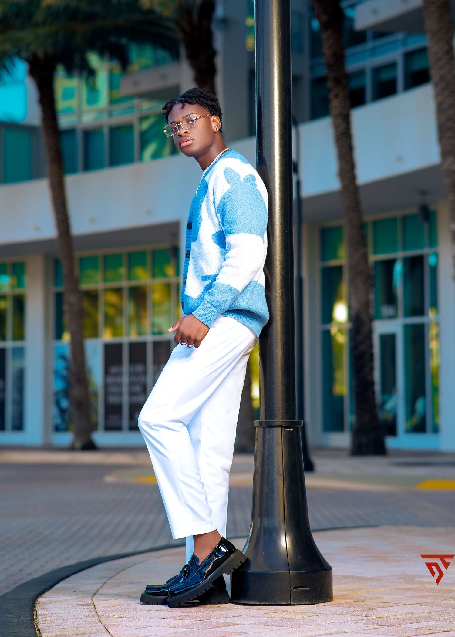 Urban fashion photography with white outfit and blue sneakers against modern building backdrop.