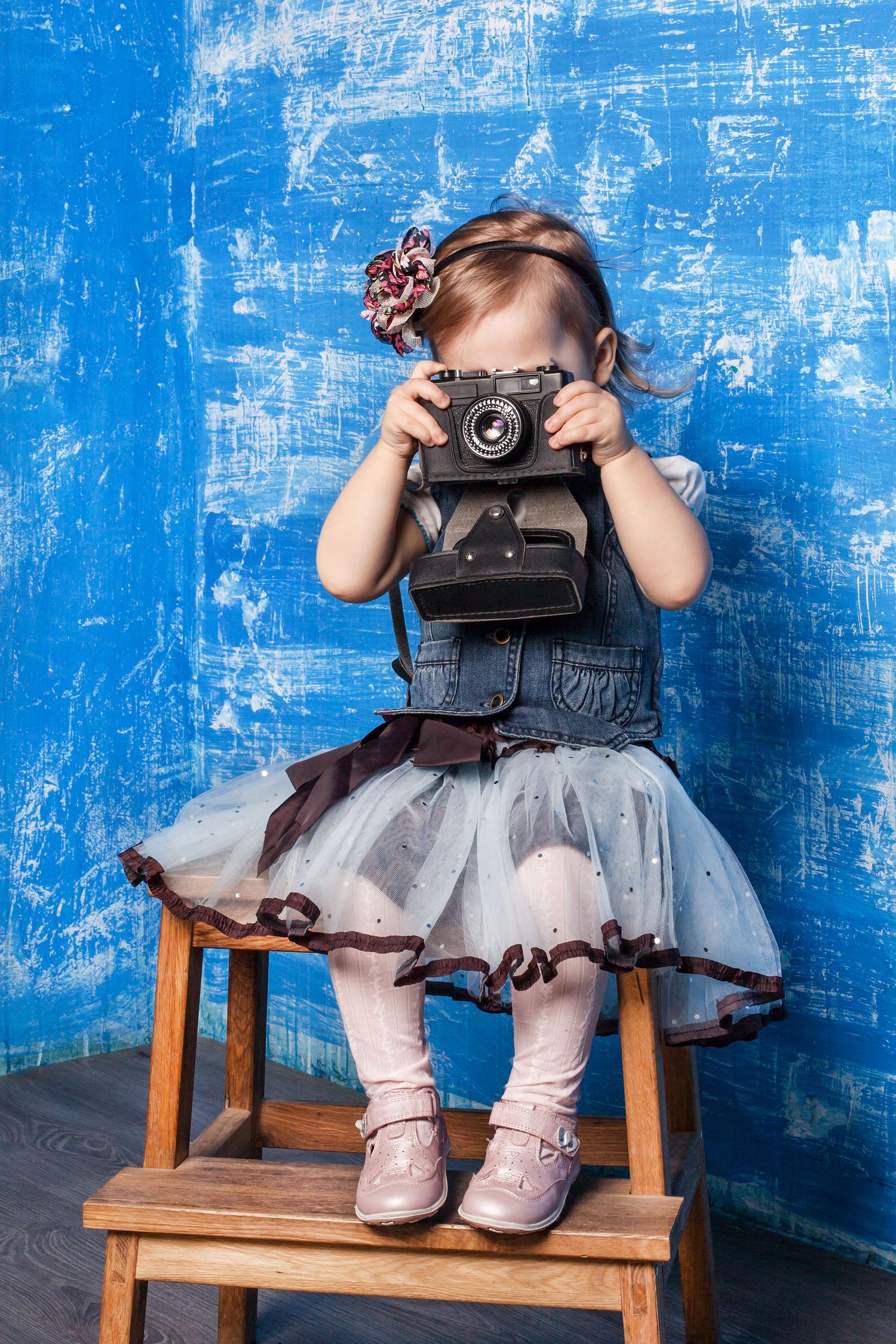 A vintage-style photo of someone holding an old camera while wearing a tulle dress.