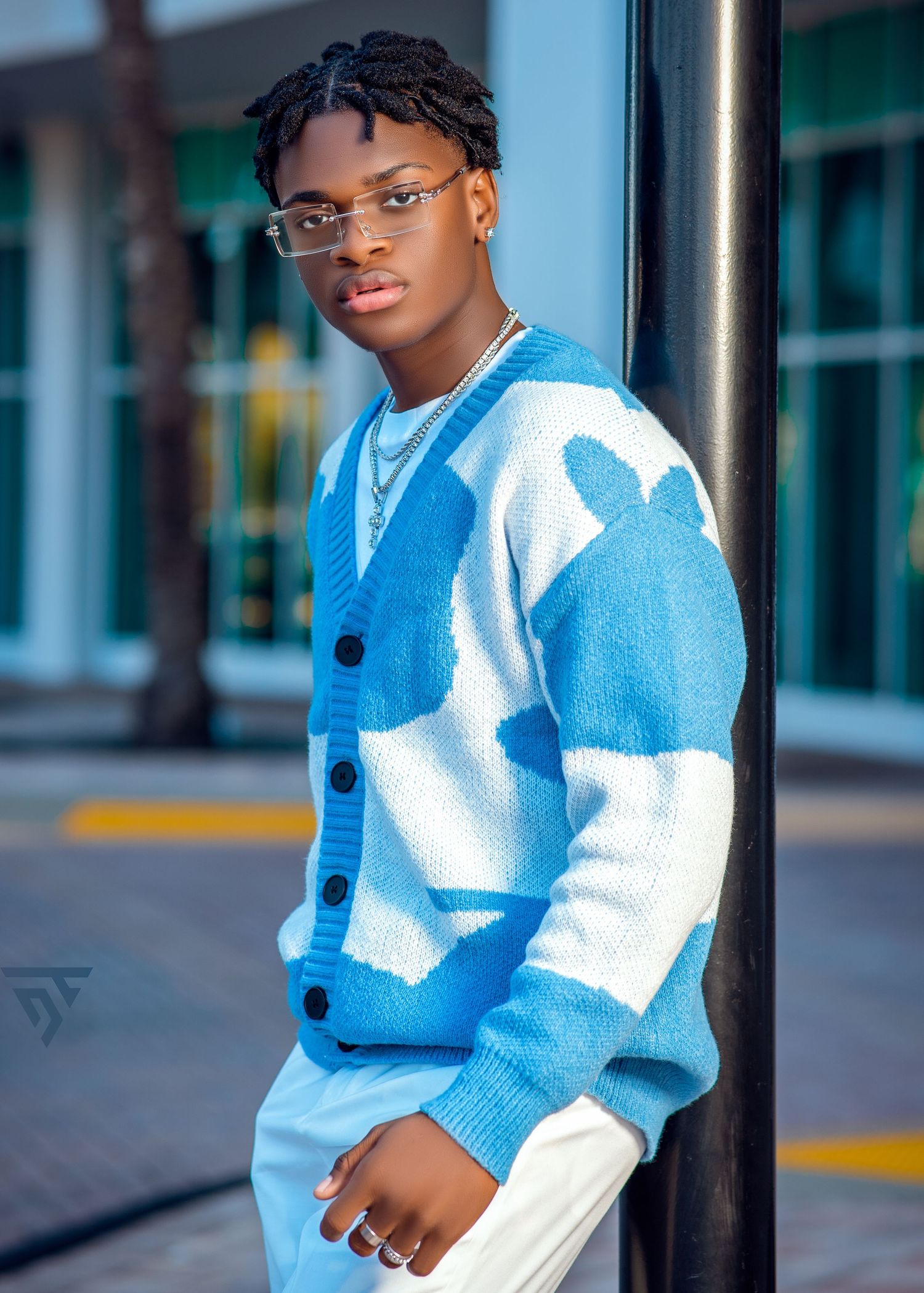Stylish two-tone blue and white cardigan sweater photographed against an urban backdrop.