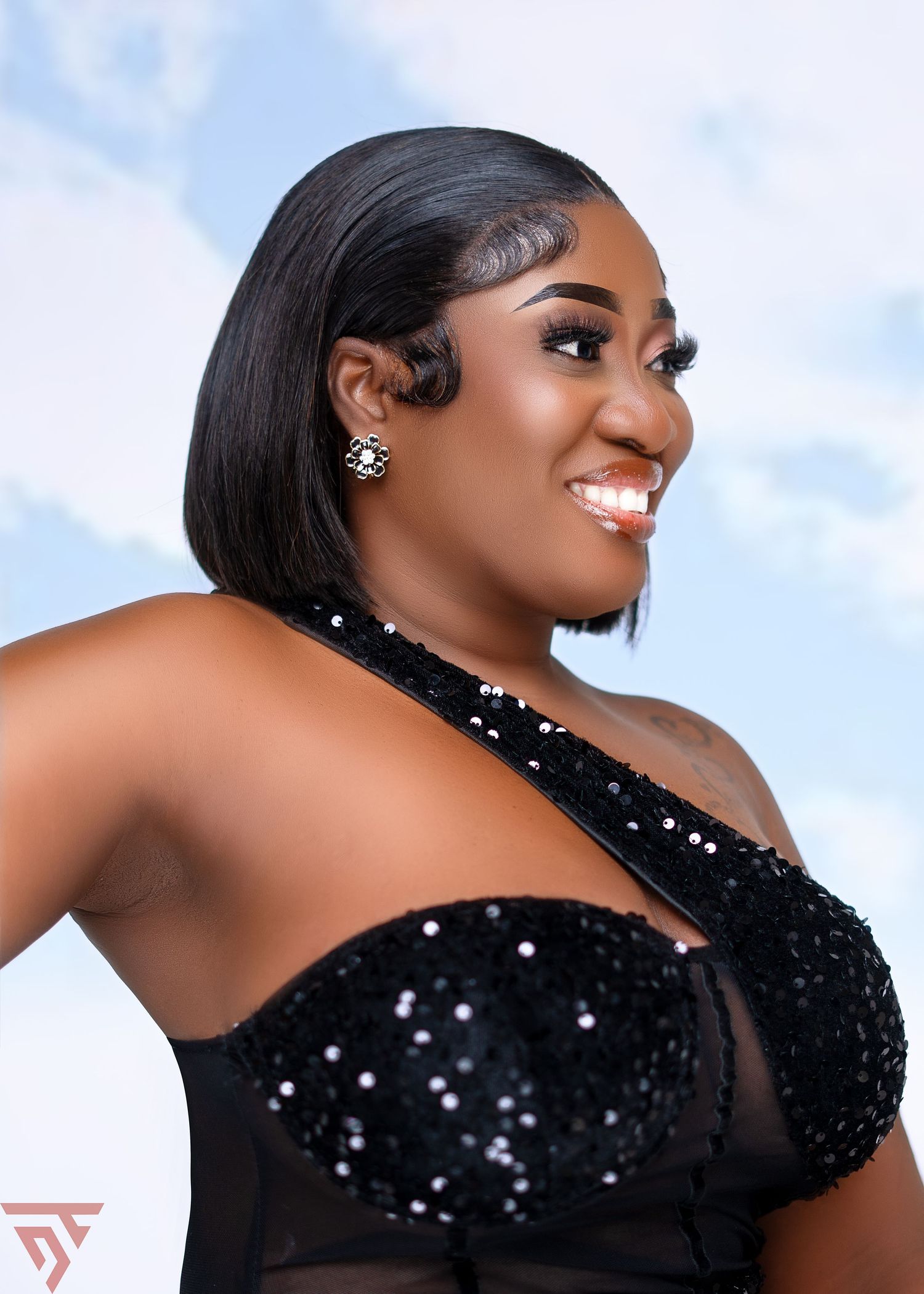 Glamorous fashion photo shoot featuring a sparkly black one-shoulder evening gown against a light background.