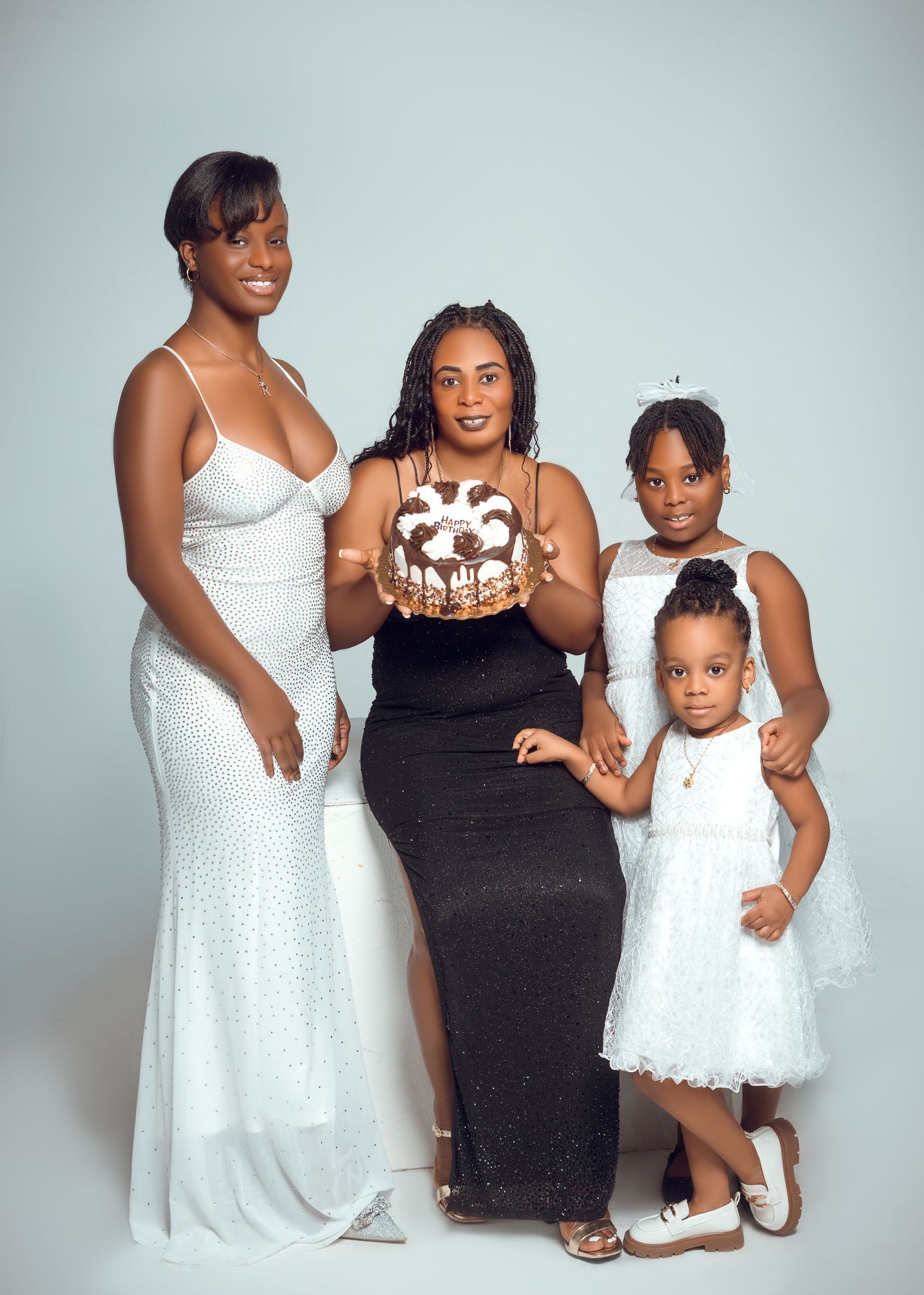 Family portrait series with coordinating white and black dresses against light background.
