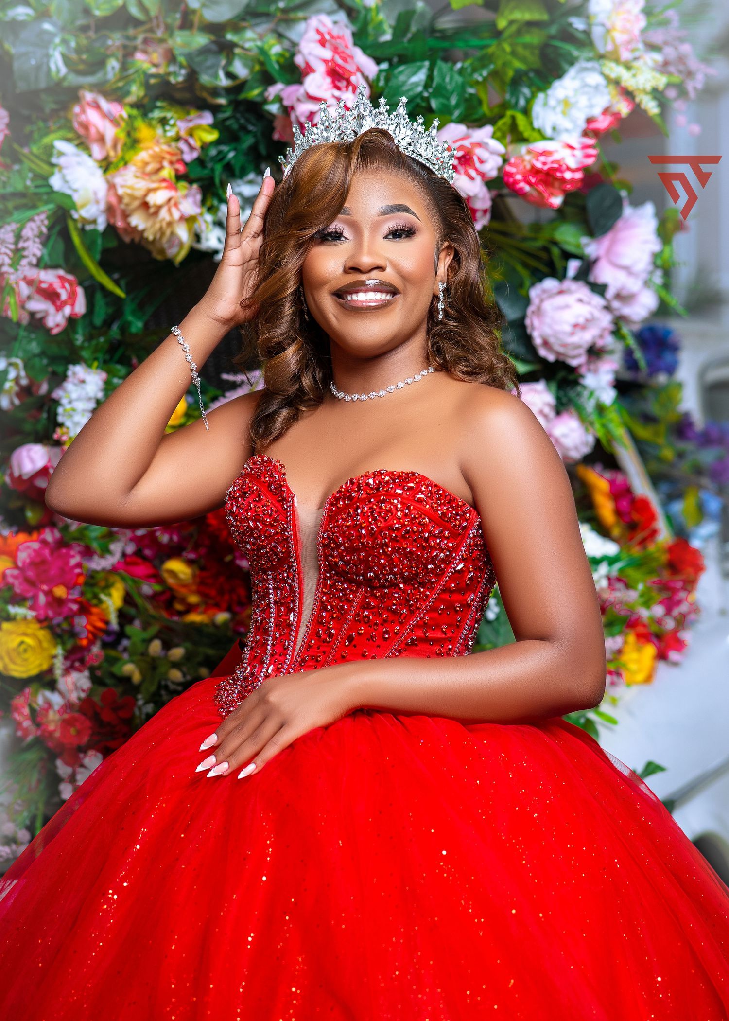 A vibrant red ballgown with crystal embellishments set against a floral backdrop.