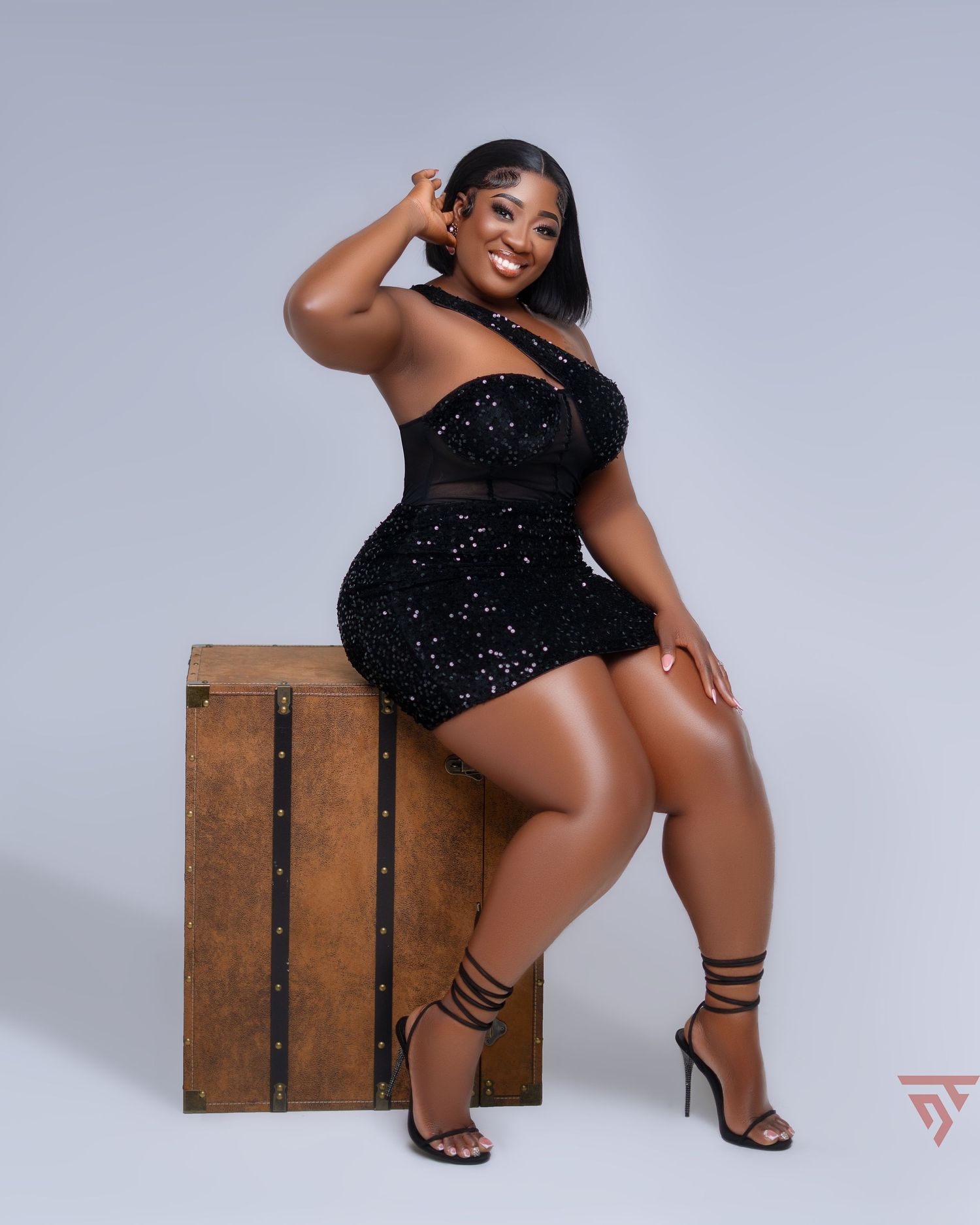 Artistic studio photoshoot featuring black sequined bodysuit and wooden prop.