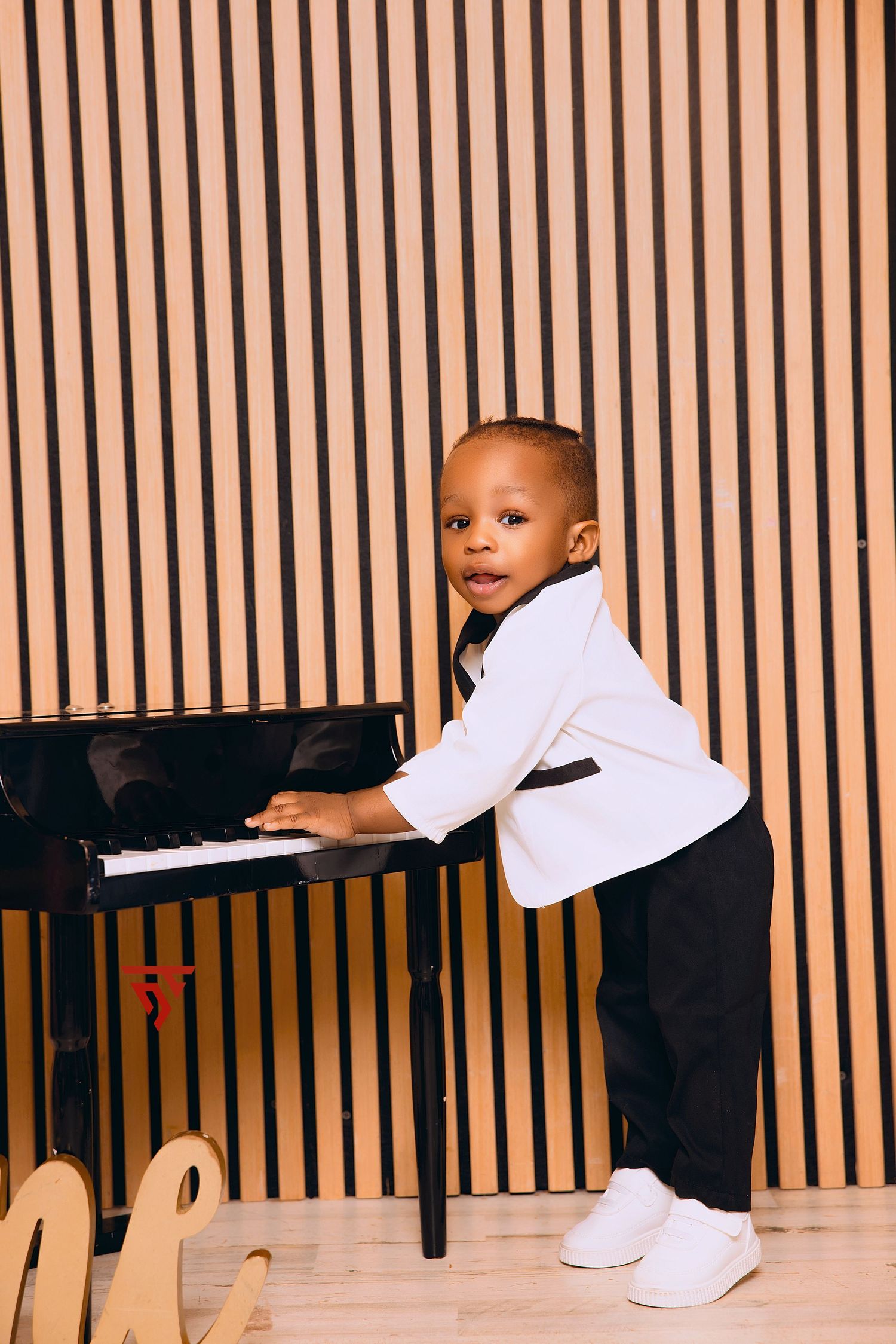 Young child playing piano in black and white outfit.