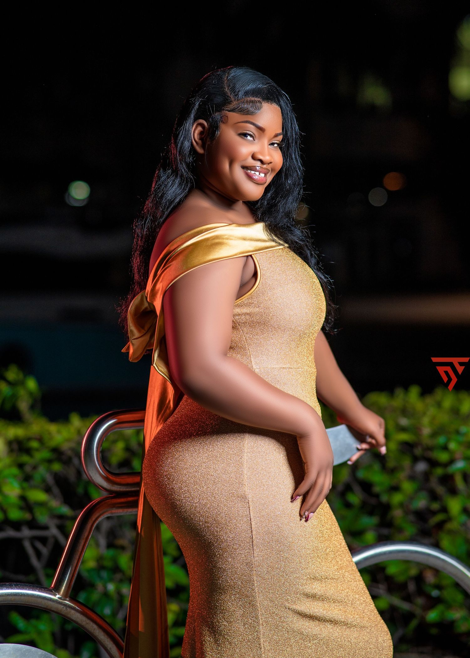 Elegant maternity photoshoot in a gold dress against a natural garden background.