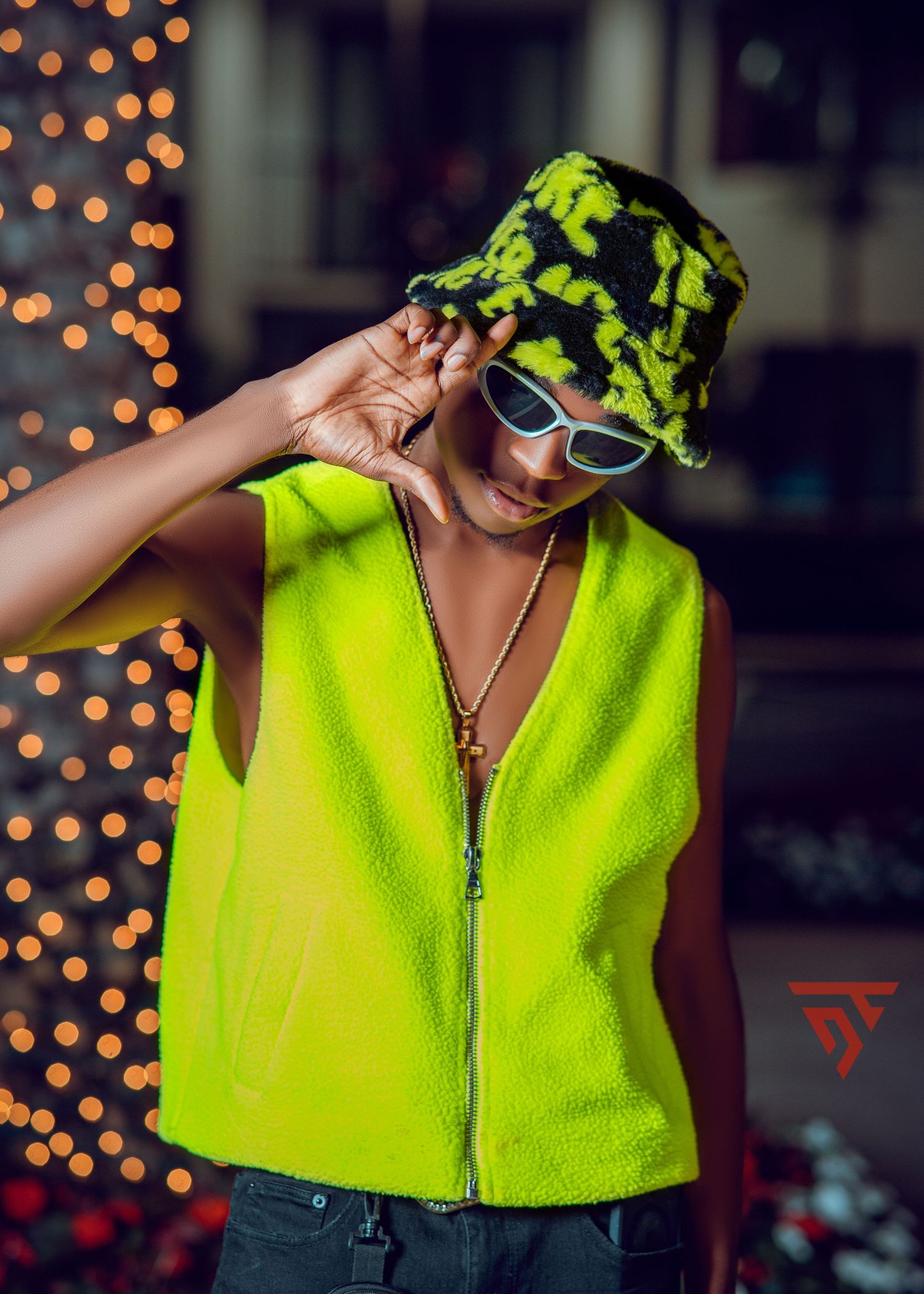 Fashion portrait in neon yellow vest and matching tie-dye bucket hat with sunglasses.