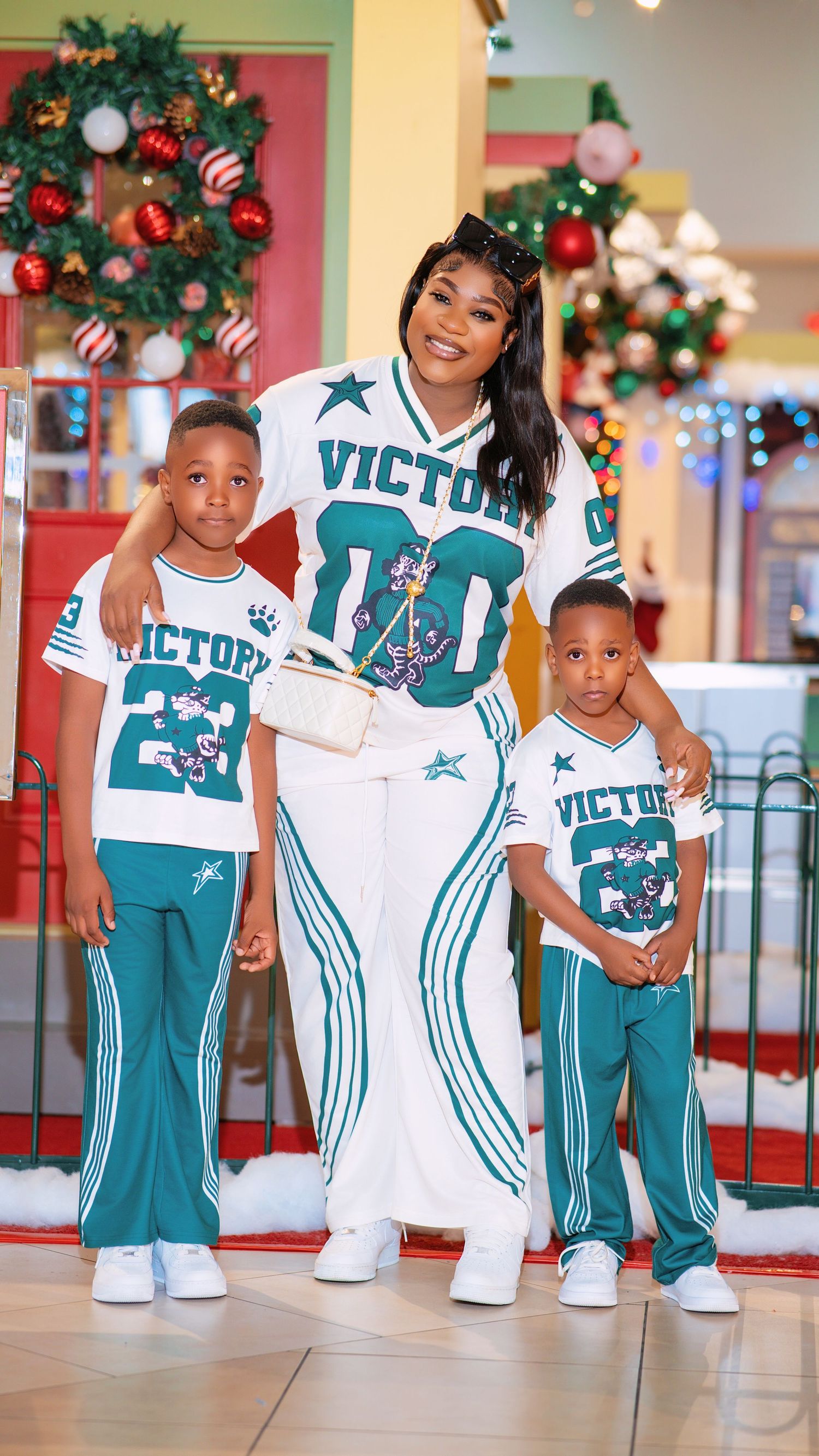 Family wearing matching Victory brand sportswear poses together in front of Christmas decorations.