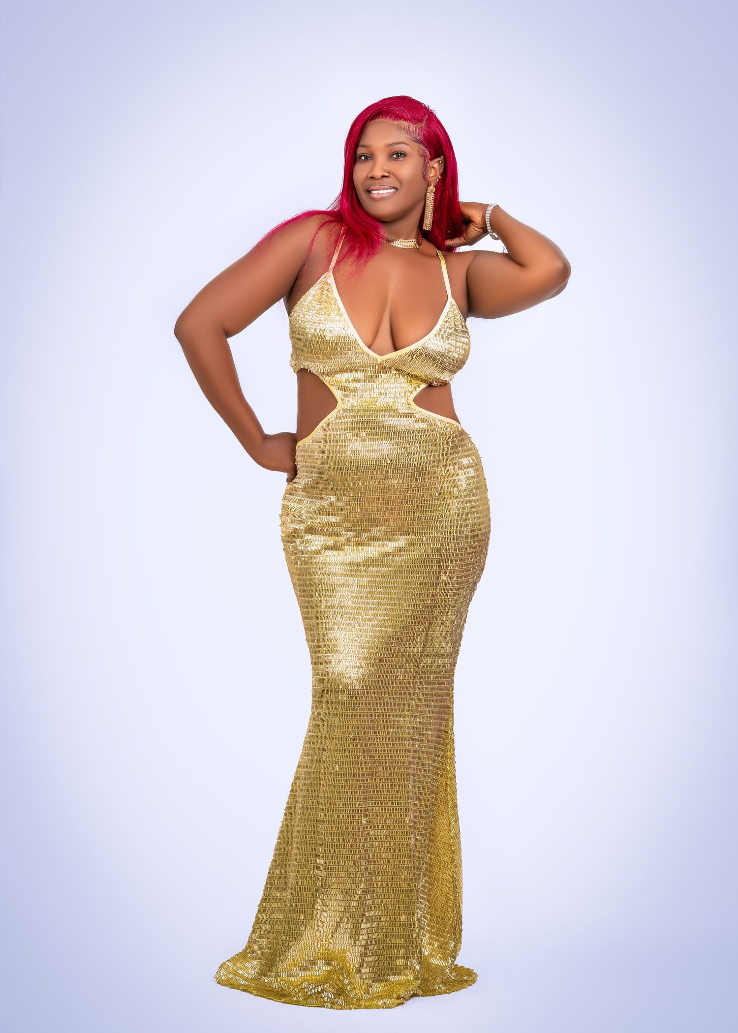Model wearing a glamorous gold sequined evening gown in a studio photoshoot.