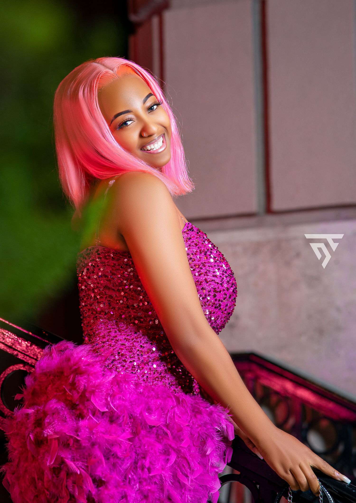 Stunning pink sequined dress with feather details captured in a glamorous outdoor portrait.