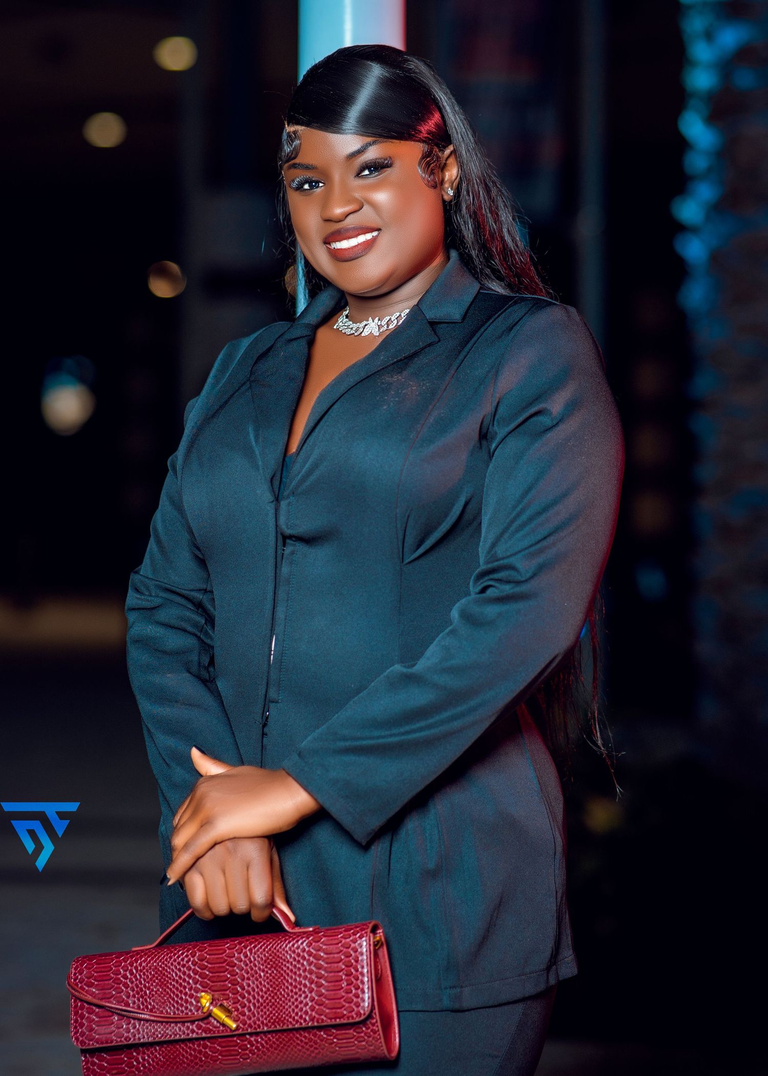 Professional look featuring teal blazer and burgundy snakeskin handbag in evening setting.