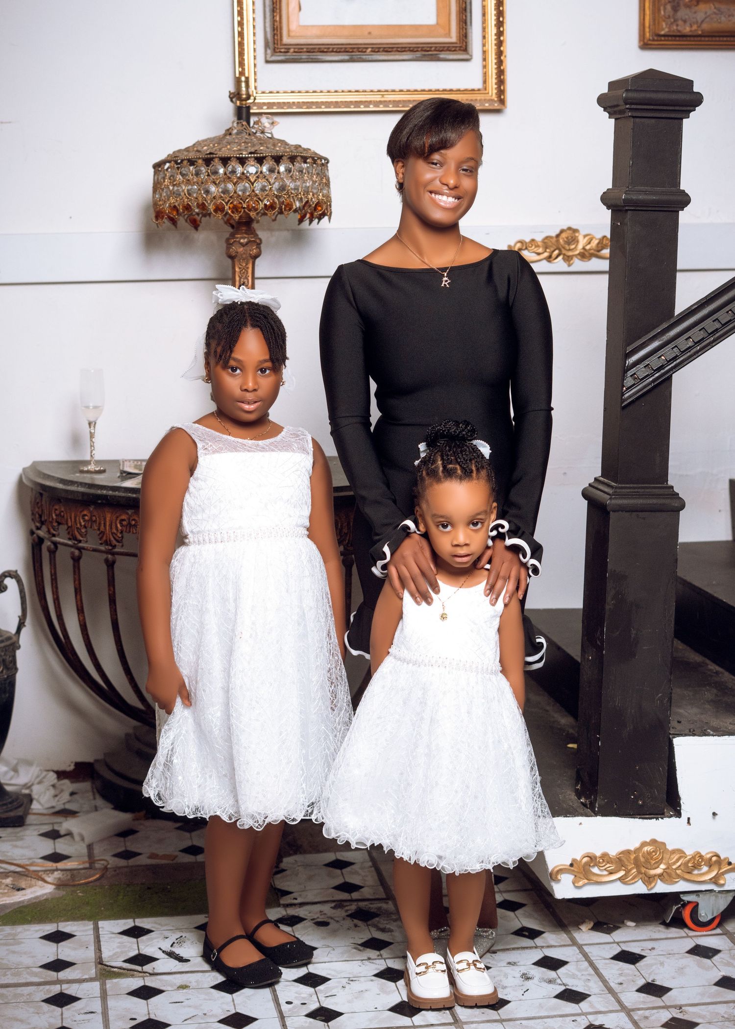 Family group wearing coordinated black and white dresses pose near ornate staircase.