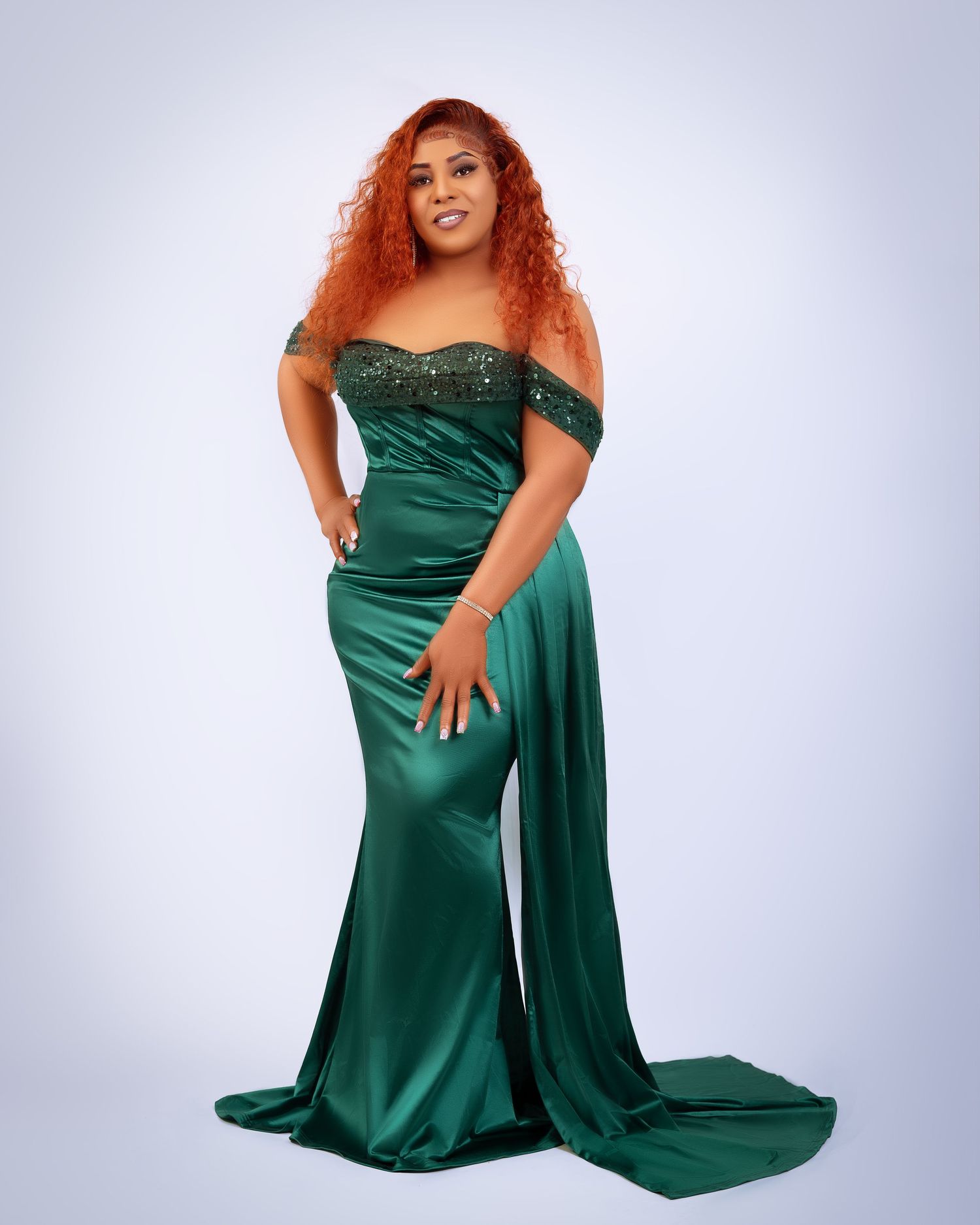 Elegant emerald green satin evening gown with off-shoulder design.