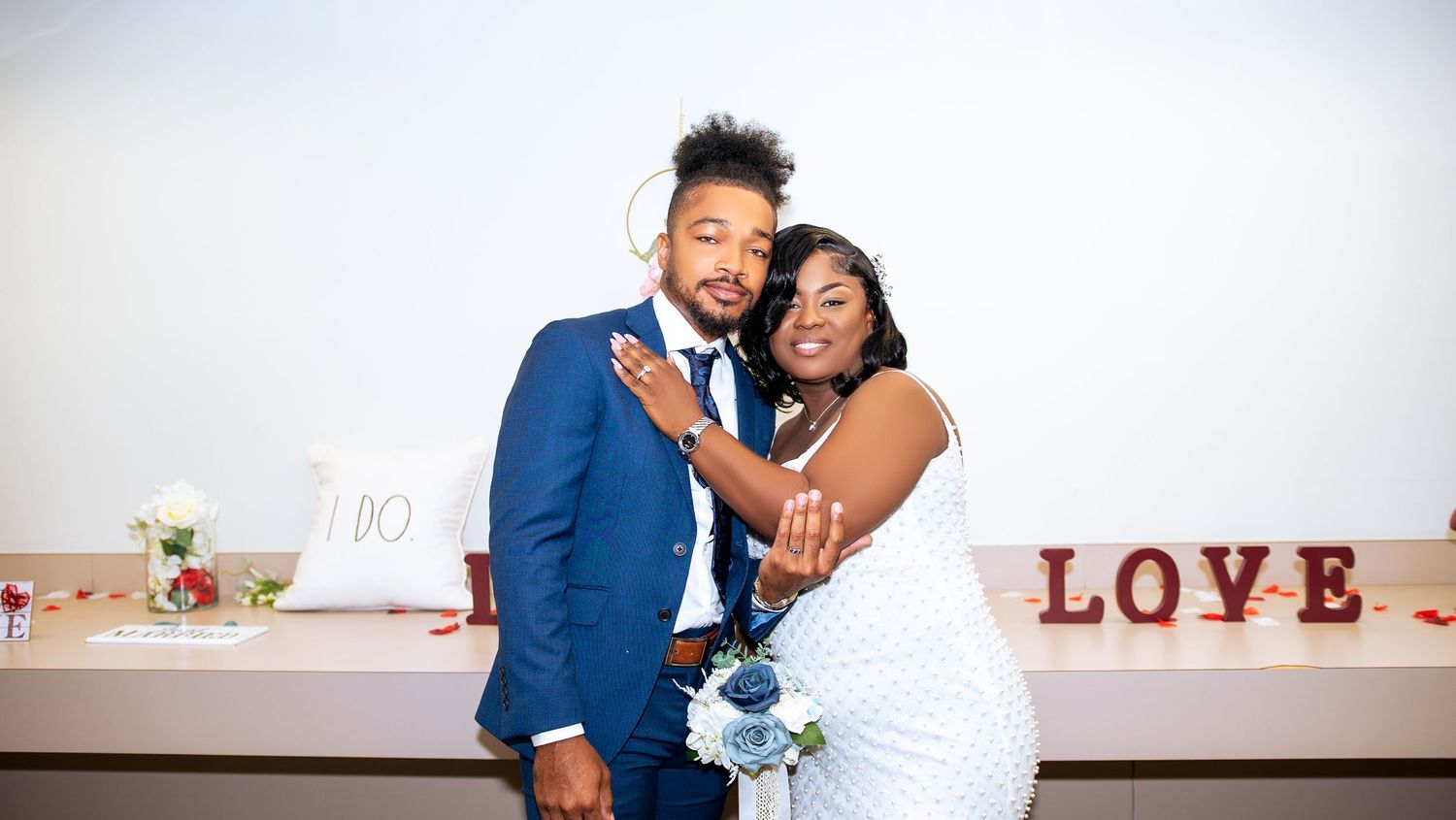 A couple poses for wedding photos with a decorative LOVE sign in the background.