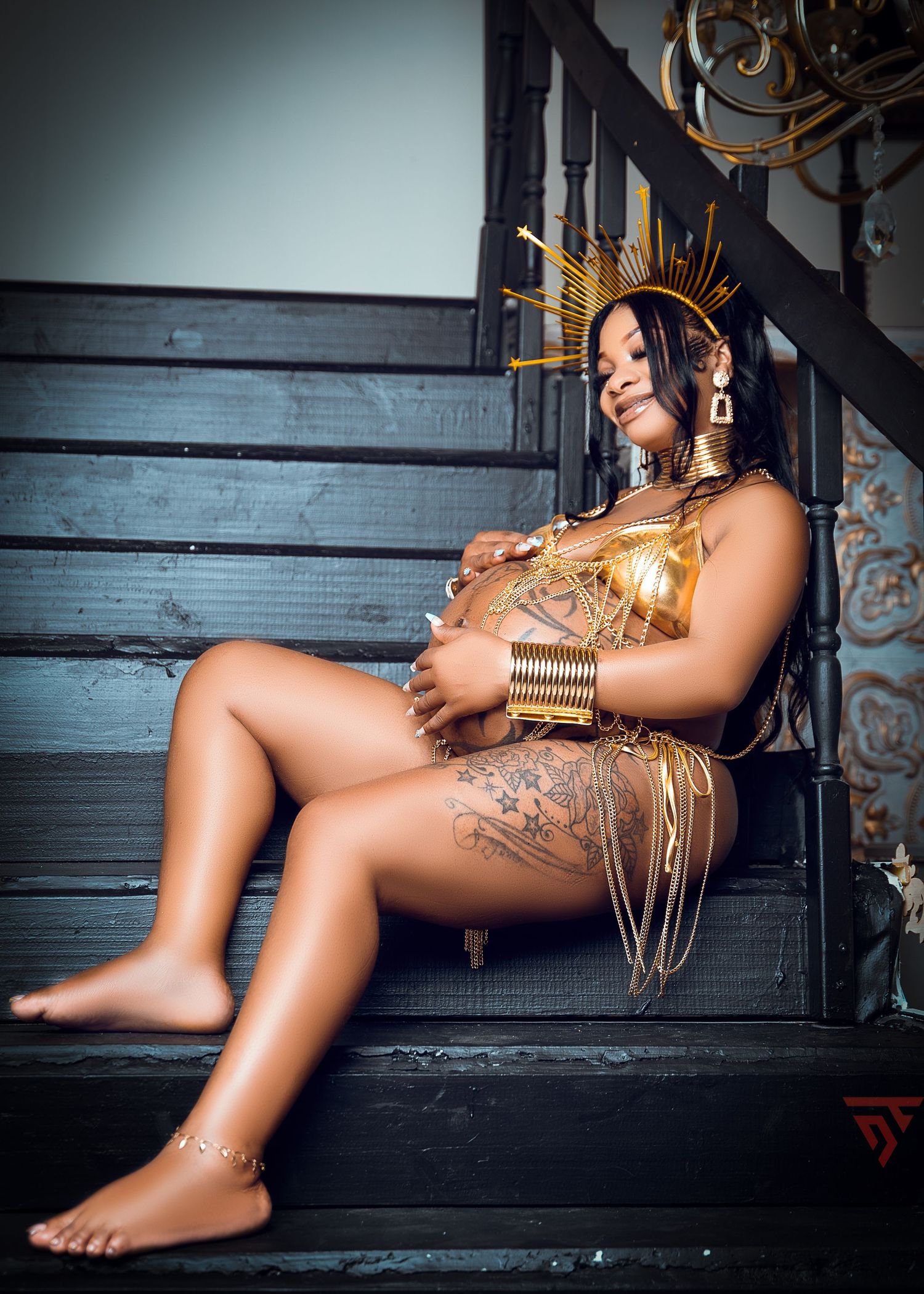 Artistic boudoir photoshoot with golden metallic body paint and dramatic lighting.
