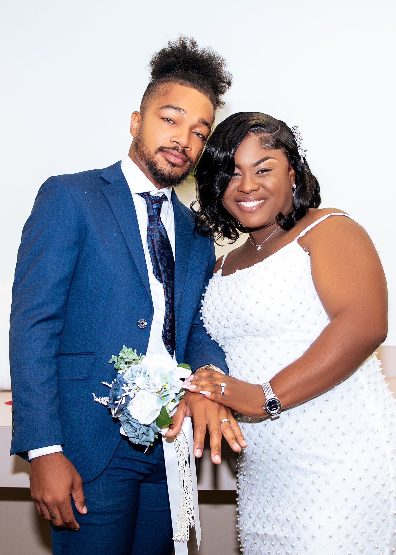 Wedding couple in navy suit and white dress share intimate poses in a romantic indoor photoshoot.