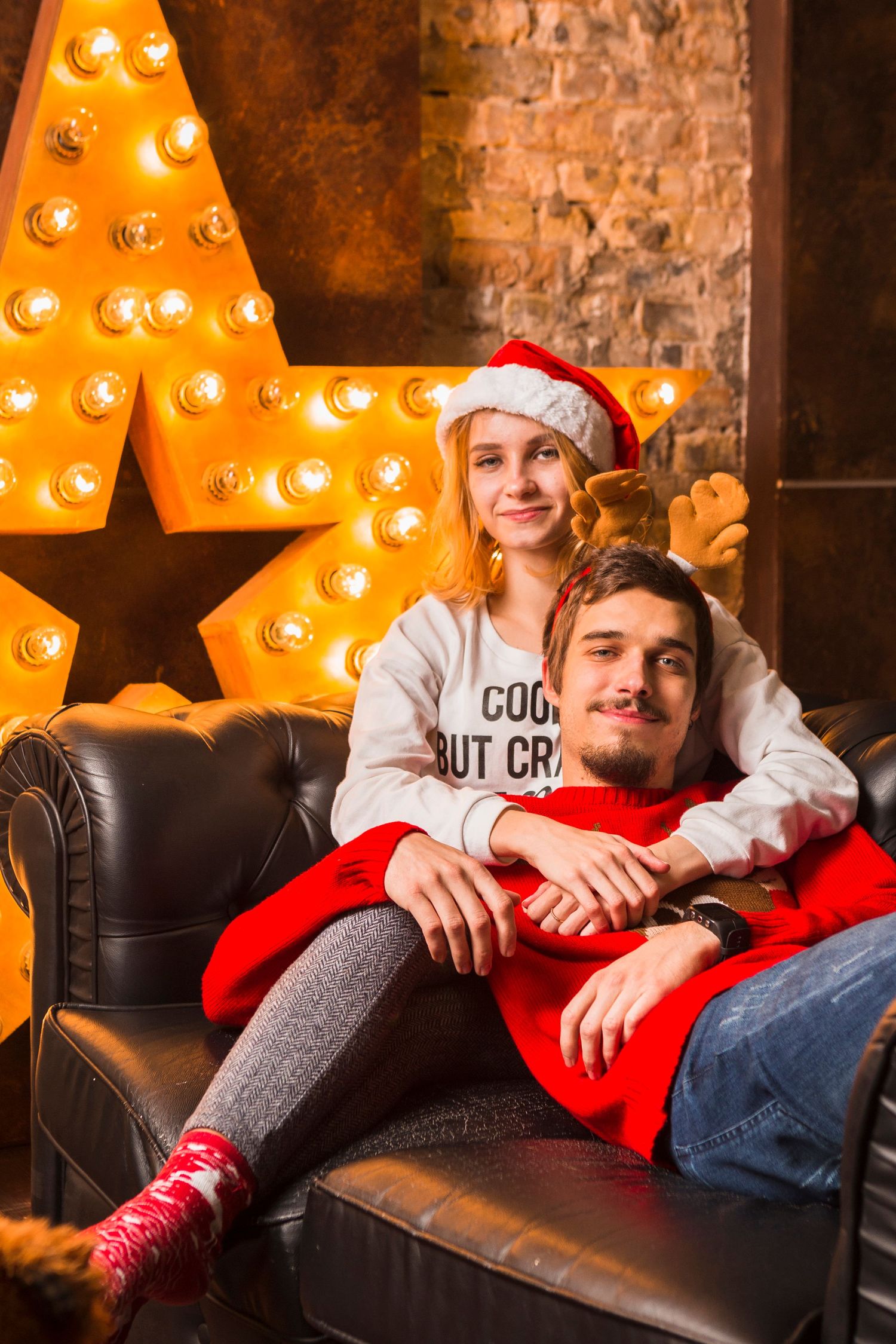 Holiday photos on leather couch with illuminated marquee letters in background.