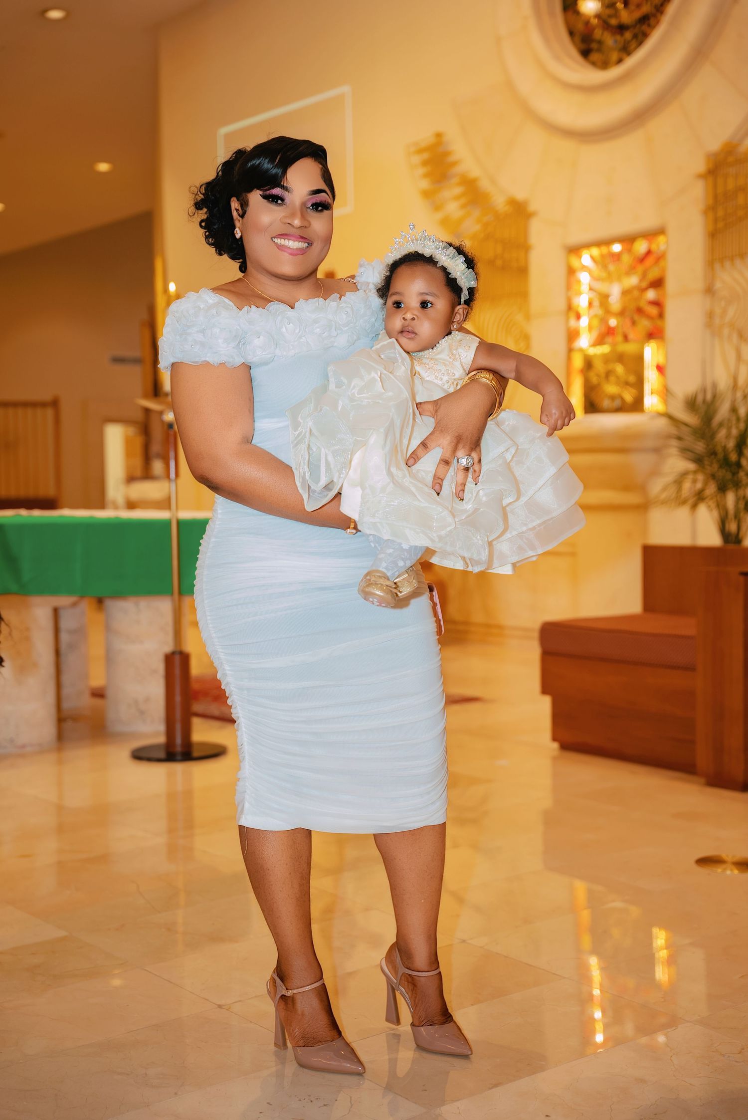 Parent and child posing together in formal attire on marble church floors.