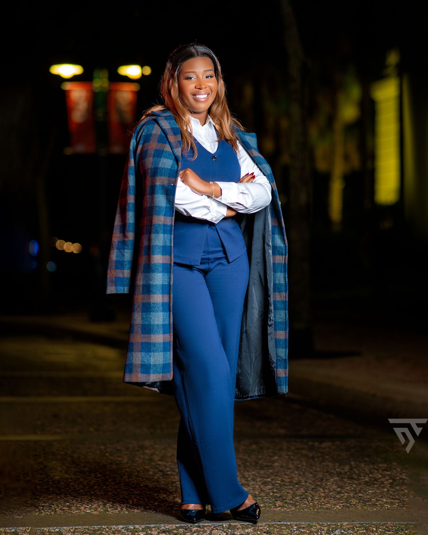 Street fashion photoshoot featuring denim overalls and plaid shirt in dark urban setting.