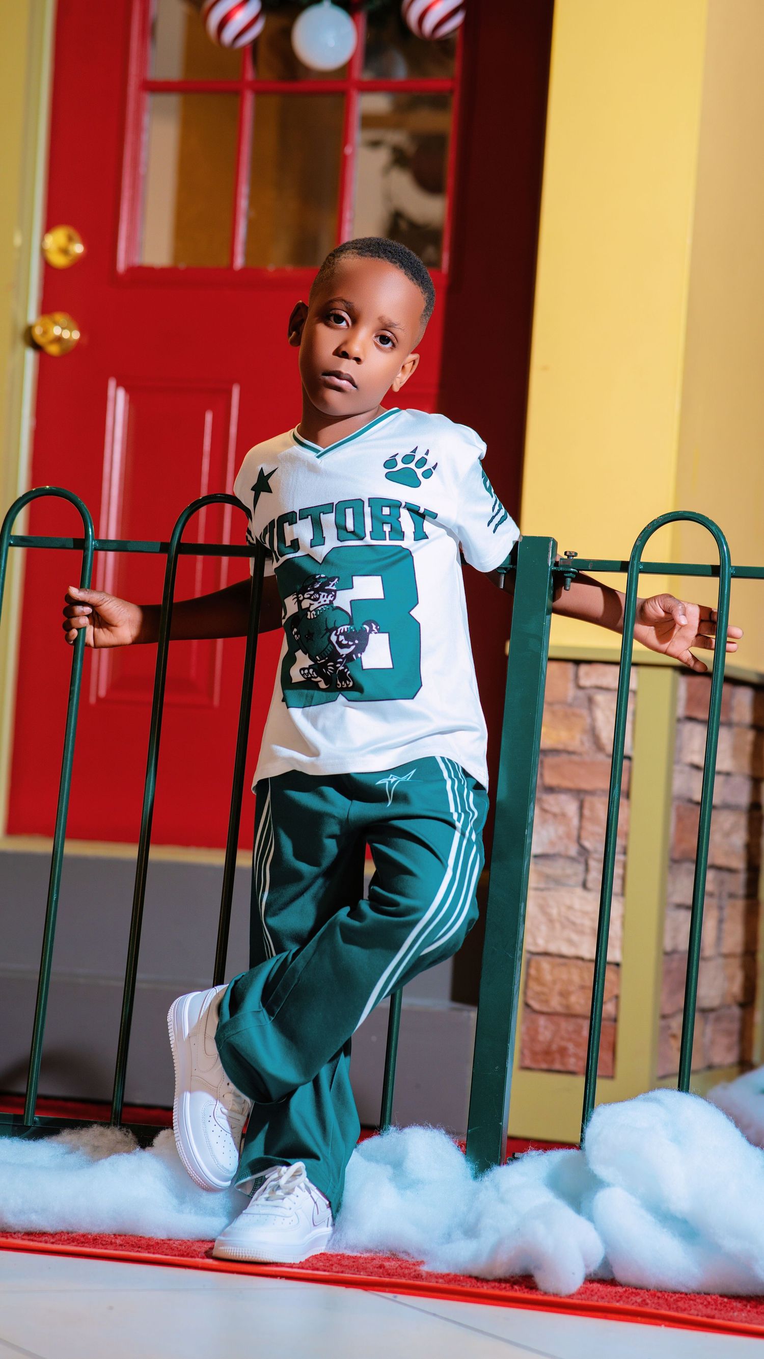 Child in teal and white sports uniform running and playing on decorated holiday set.