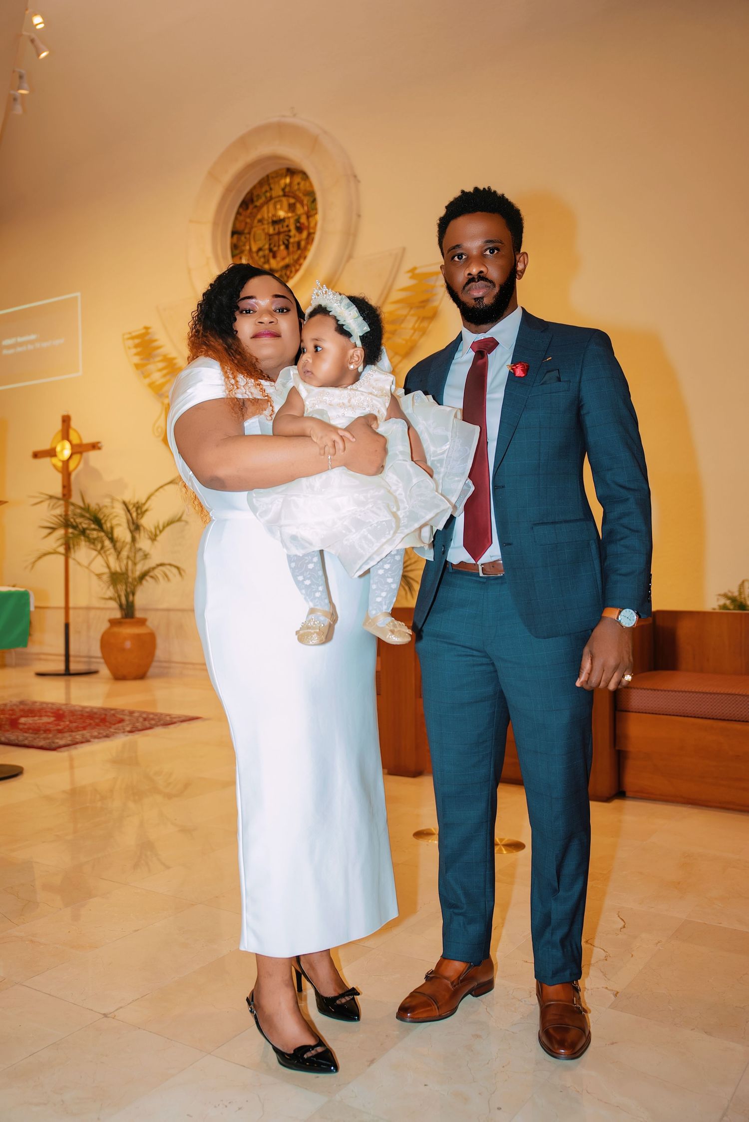 Family group photo in formal attire at church baptism ceremony.