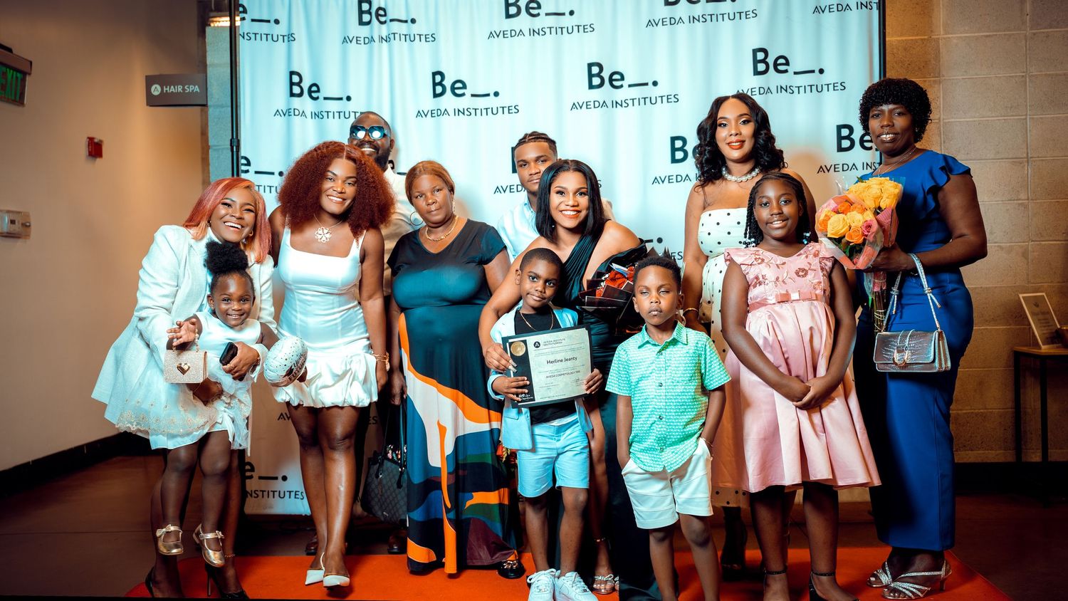 People gathered for a group photo at an indoor event with branded backdrop.
