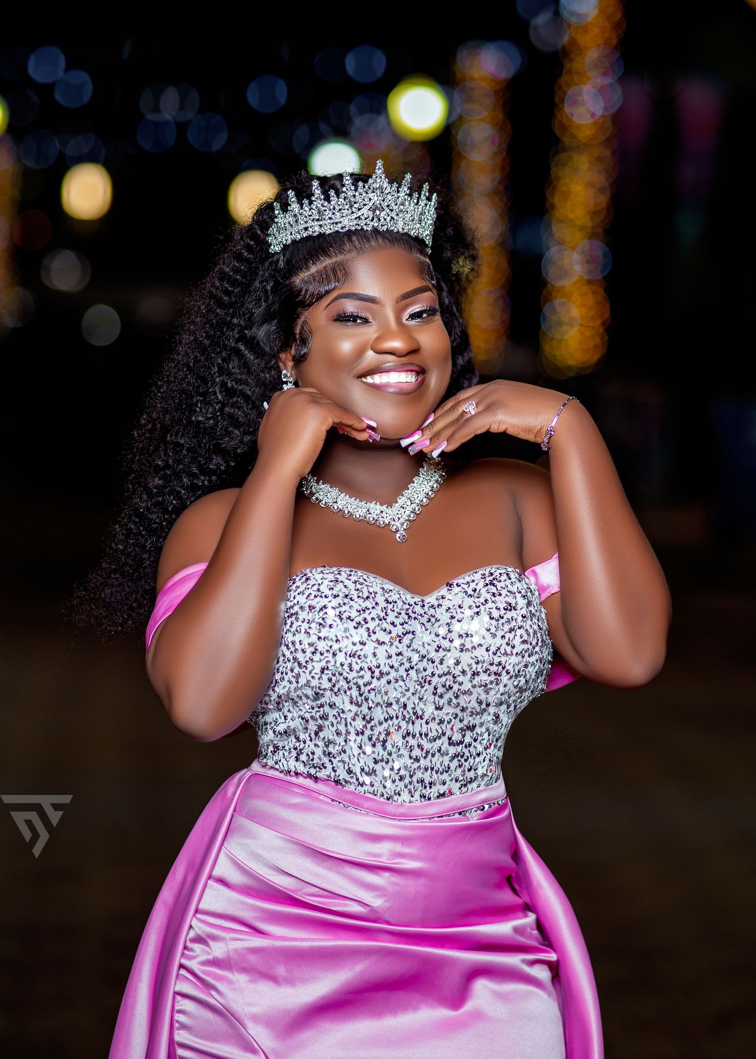 A glamorous pink satin gown adorned with crystals and a sparkling tiara.