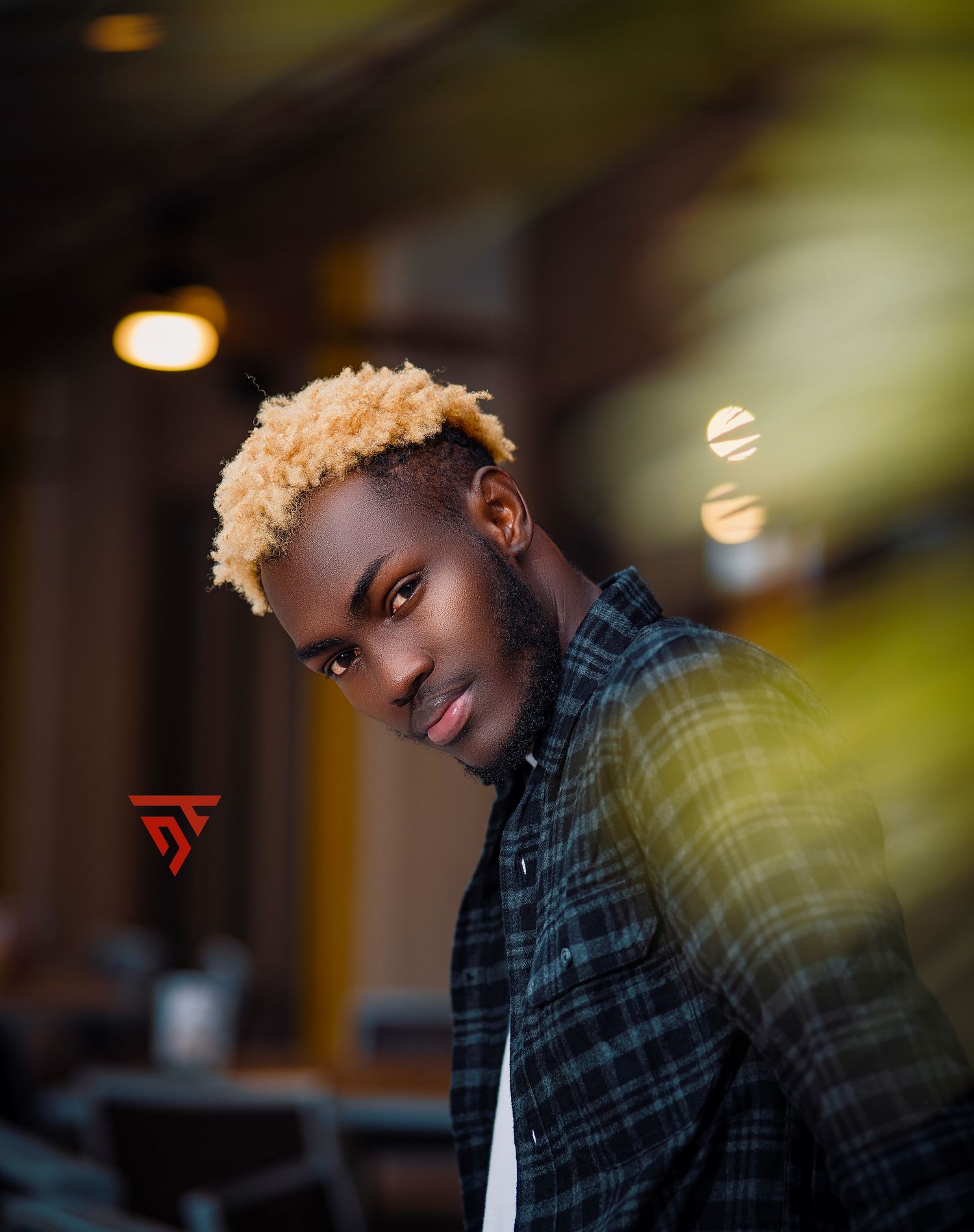 Portrait of someone with blonde hair wearing plaid shirt in atmospheric lighting.