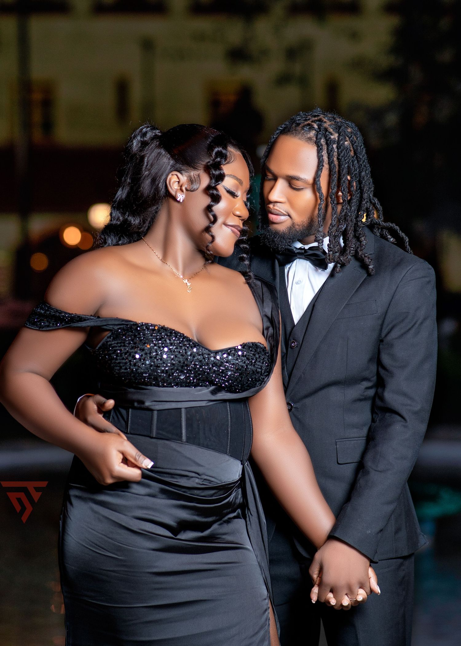Elegant couple in formal black evening wear share intimate moments during photoshoot.